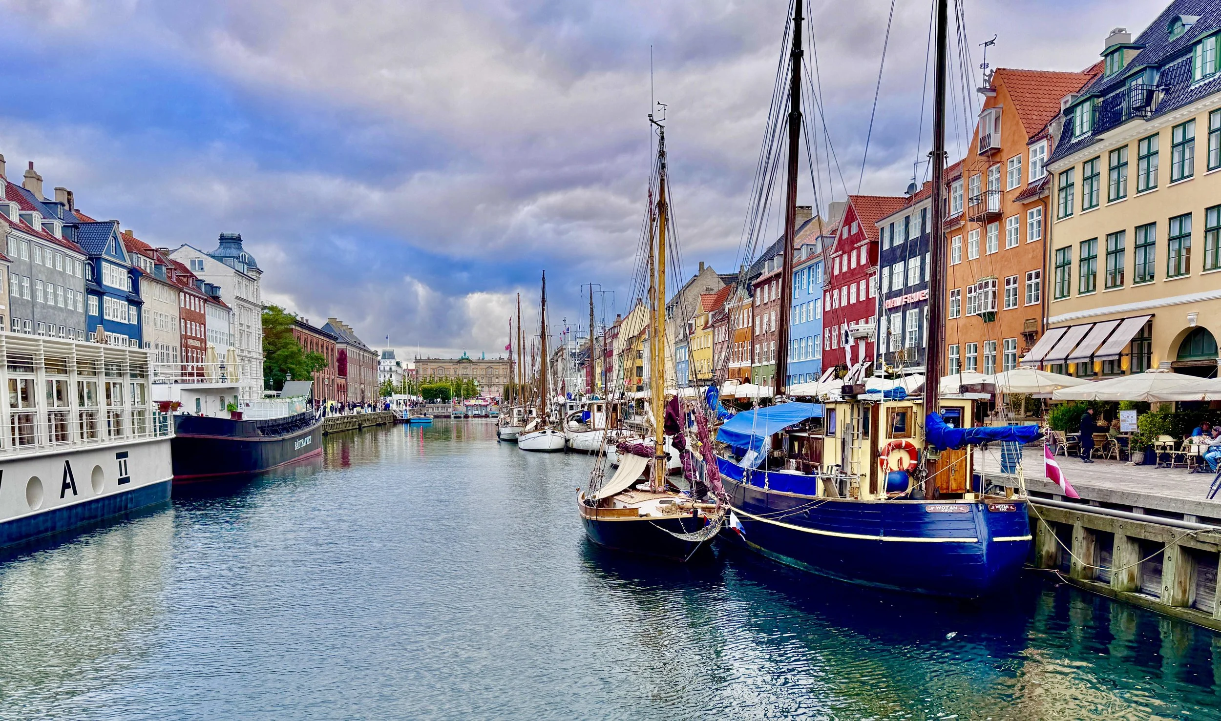 Colorful row of buildings lining a harbor filled with boats, under a cloudy sky.