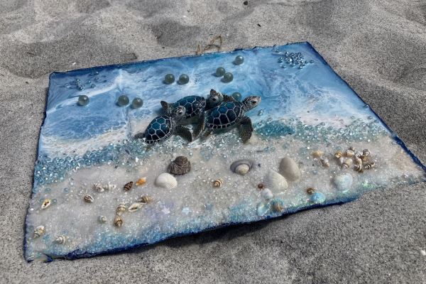 Miniature ocean scene with tiny turtles, seashells, and beads on a sandy surface.