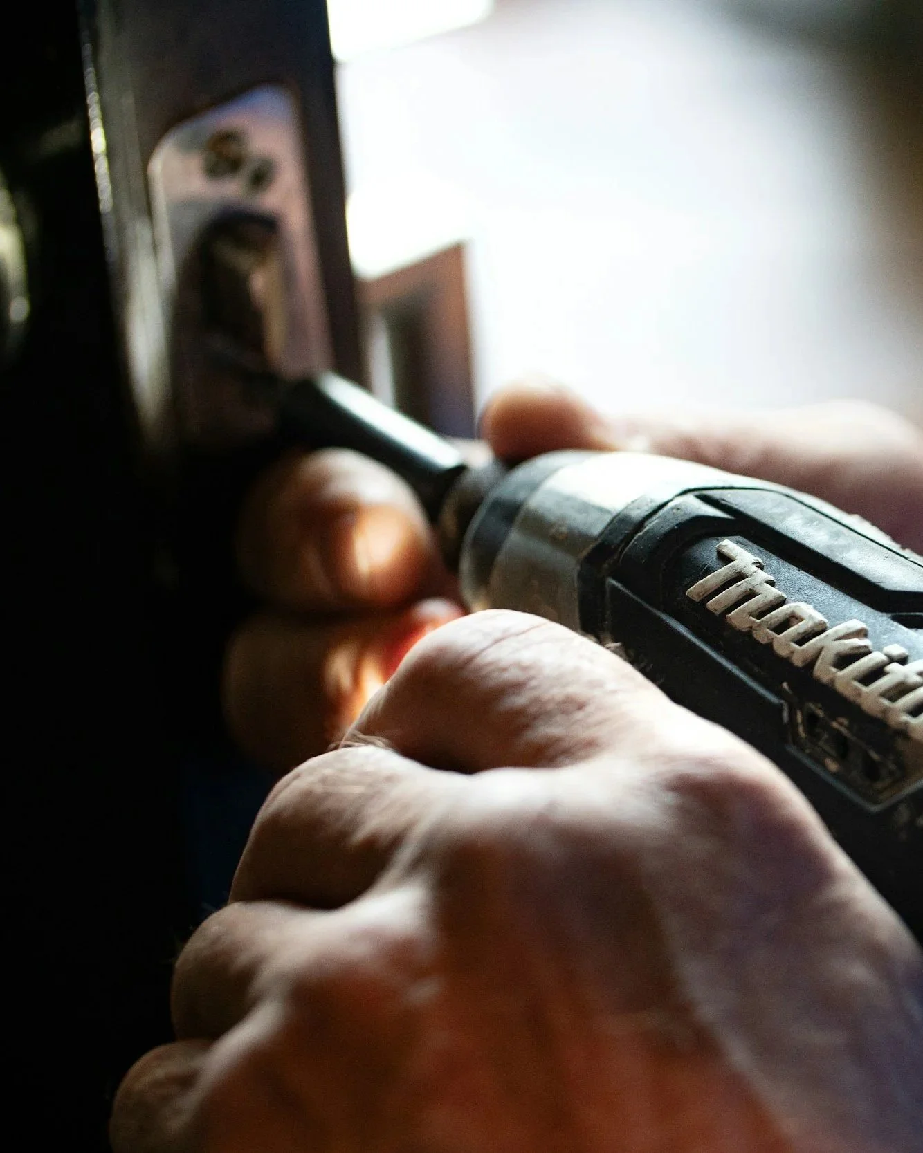 Zlota technician using a cordless drill during a building maintenance job.