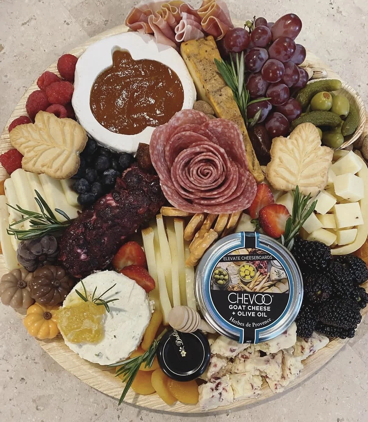 A cheese board with assorted cheeses, cured meats, crackers, grapes, berries, and spreads.