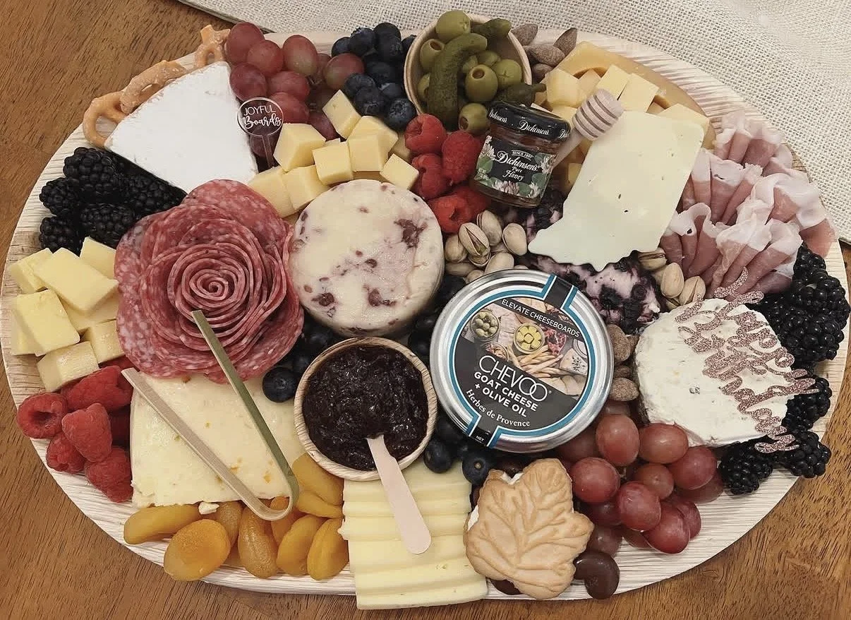 A cheese and charcuterie board with various cheeses, cured meats, fruits, nuts, and spreads.