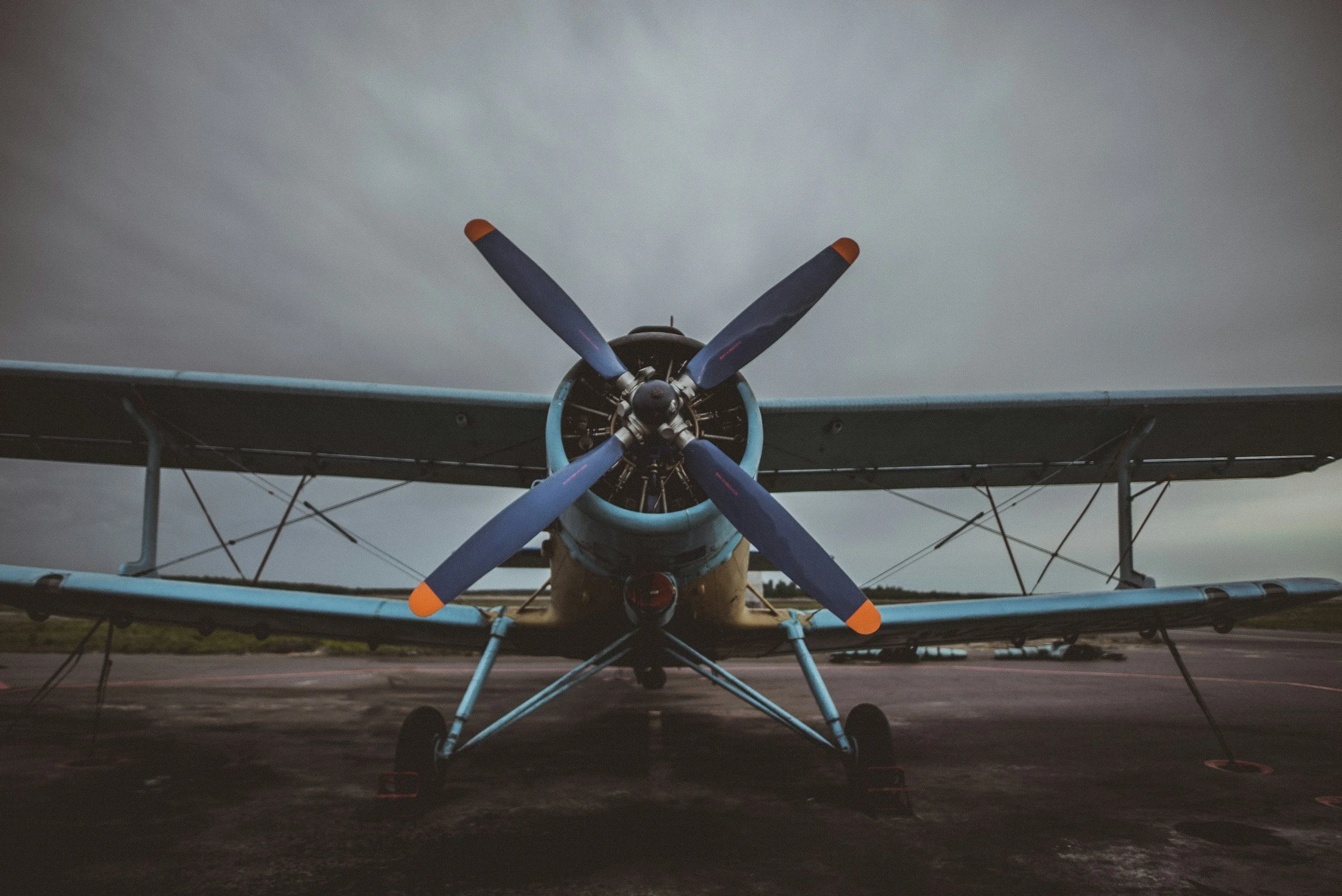 Front view of a vintage biplane airplane on a runway during overcast weather.