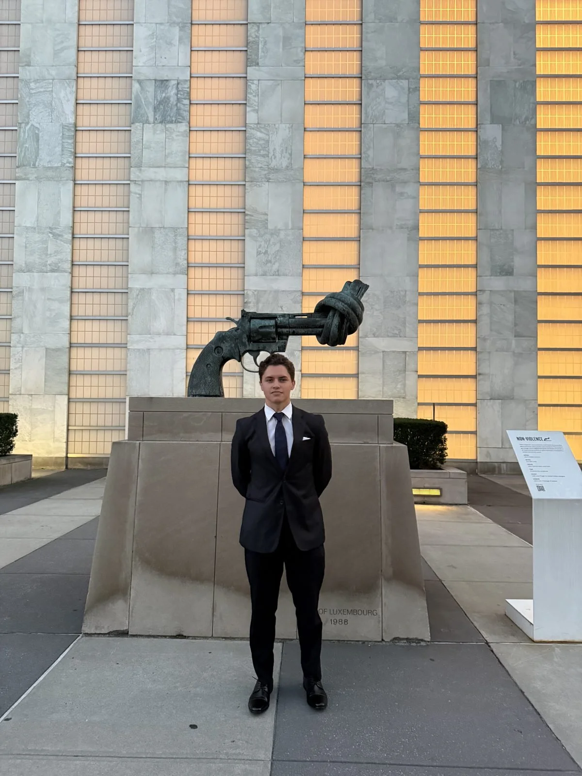 Lucas A. Perry standing beside the Knotted Gun peace sculpture in the plaza outside United Nations Headquarters in New York City.