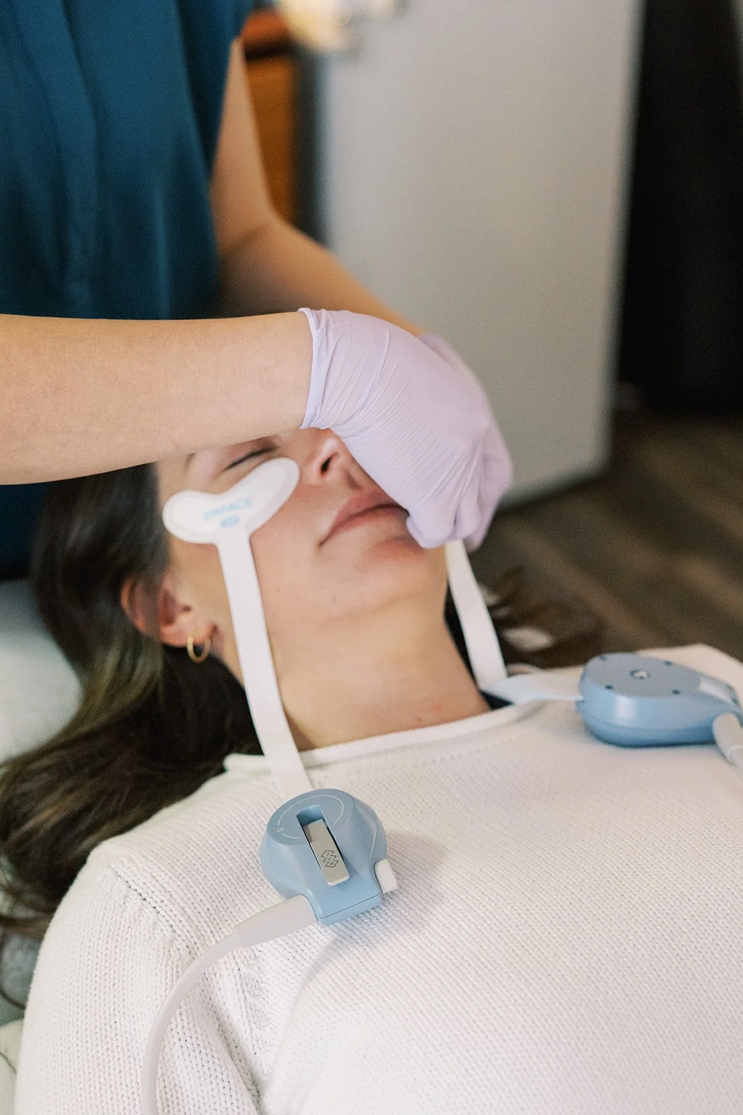 Person lying down receiving a nasal swab test from a healthcare worker wearing gloves.