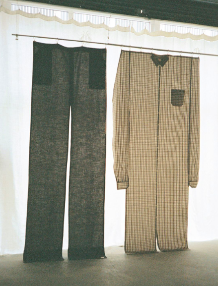 Pair of pajamas hanging on a line, with checkered pattern on a beige background and dark-colored pants.
