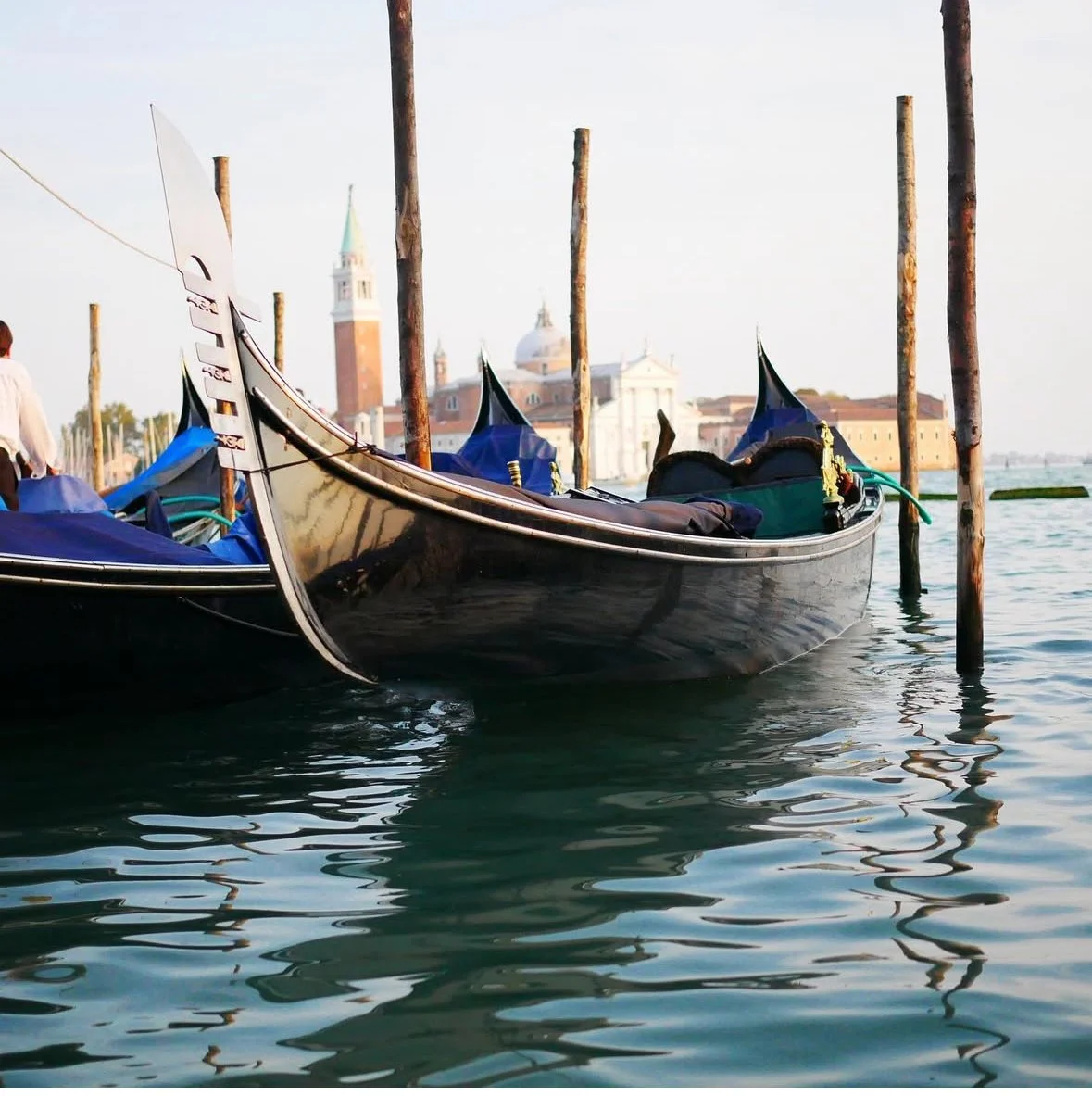 Venetian gondolas moored along a canal with historic buildings in the background.