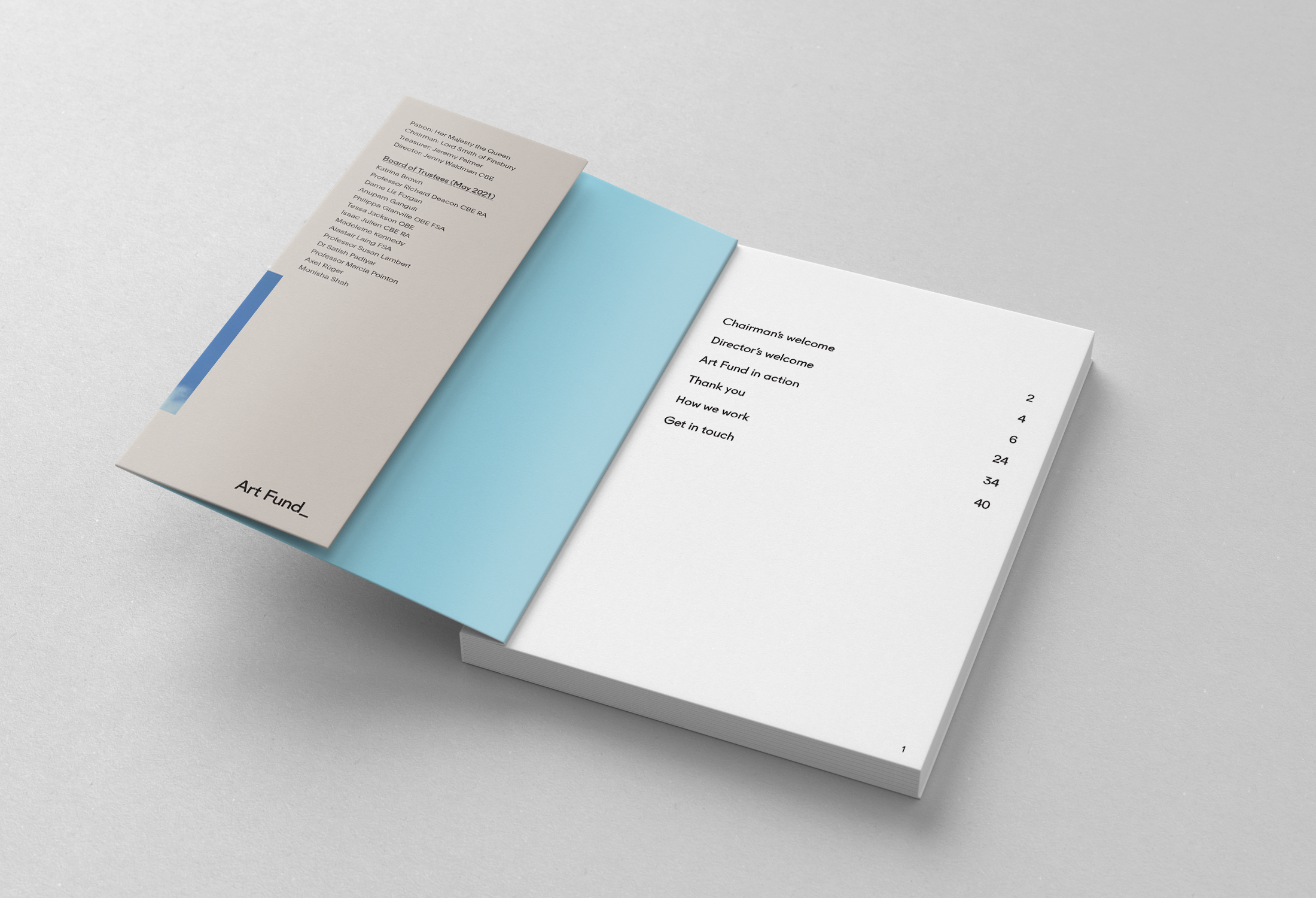 Open booklet or brochure with a white and light blue inside, showing a table of contents and some text about an art fund or art event, placed on a white surface.