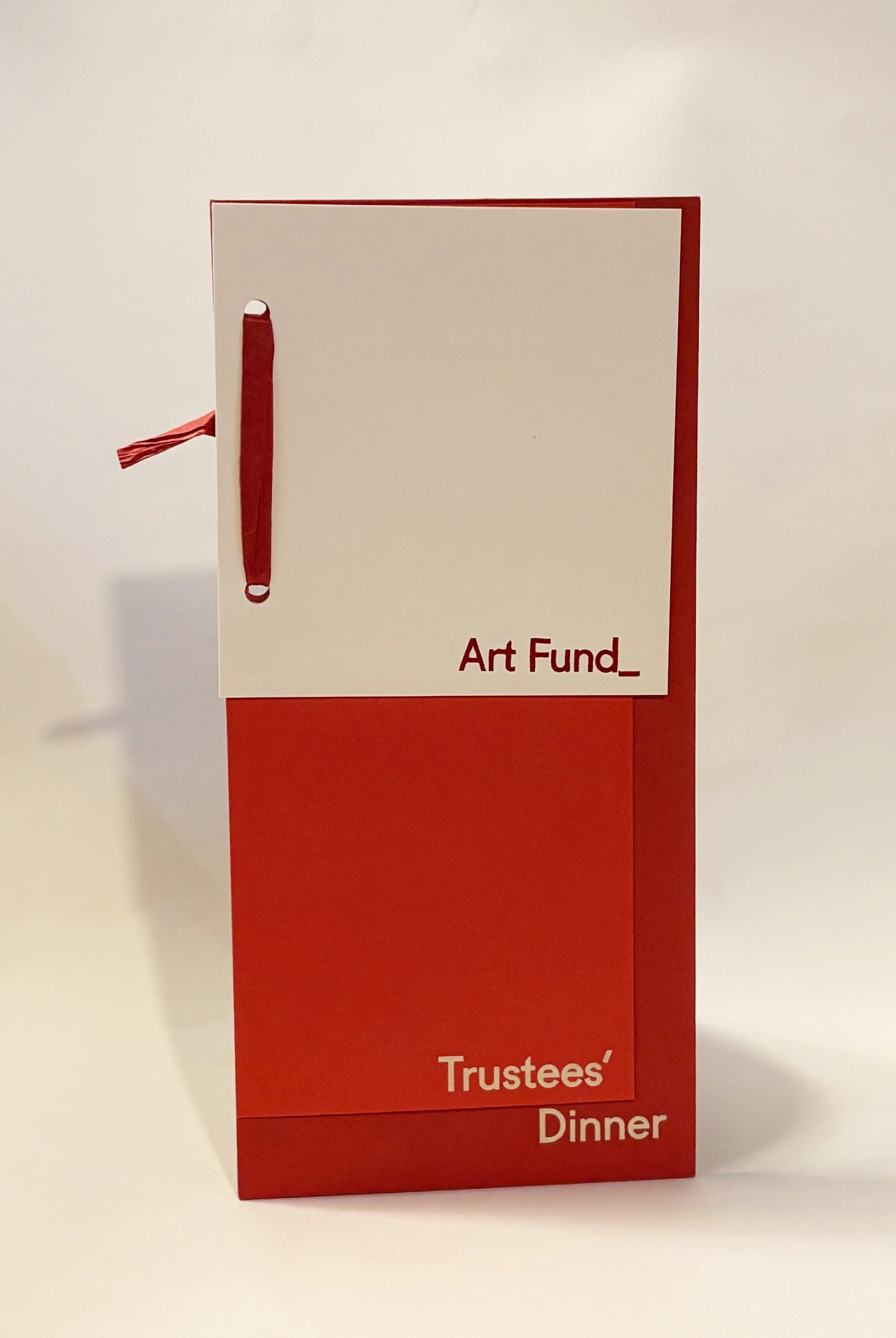 Red and white paper menu with a red ribbon bookmark, titled "Trustees' Dinner" in red text.