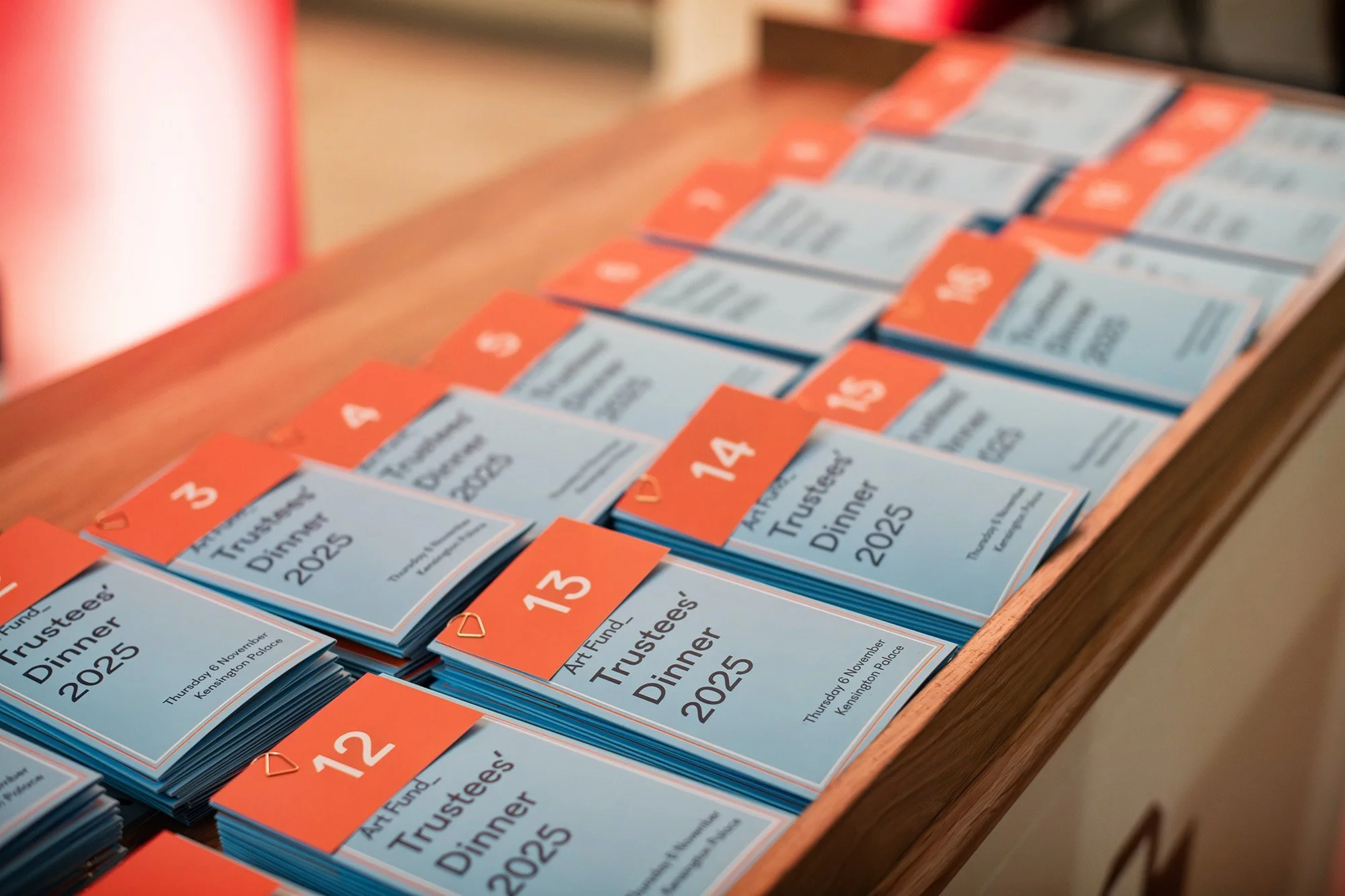 Stack of event programs for the Art Fund Trustee Dinner 2025, dated Thursday, November 6, at Kensington Palace, with red and blue covers and numbered tabs.