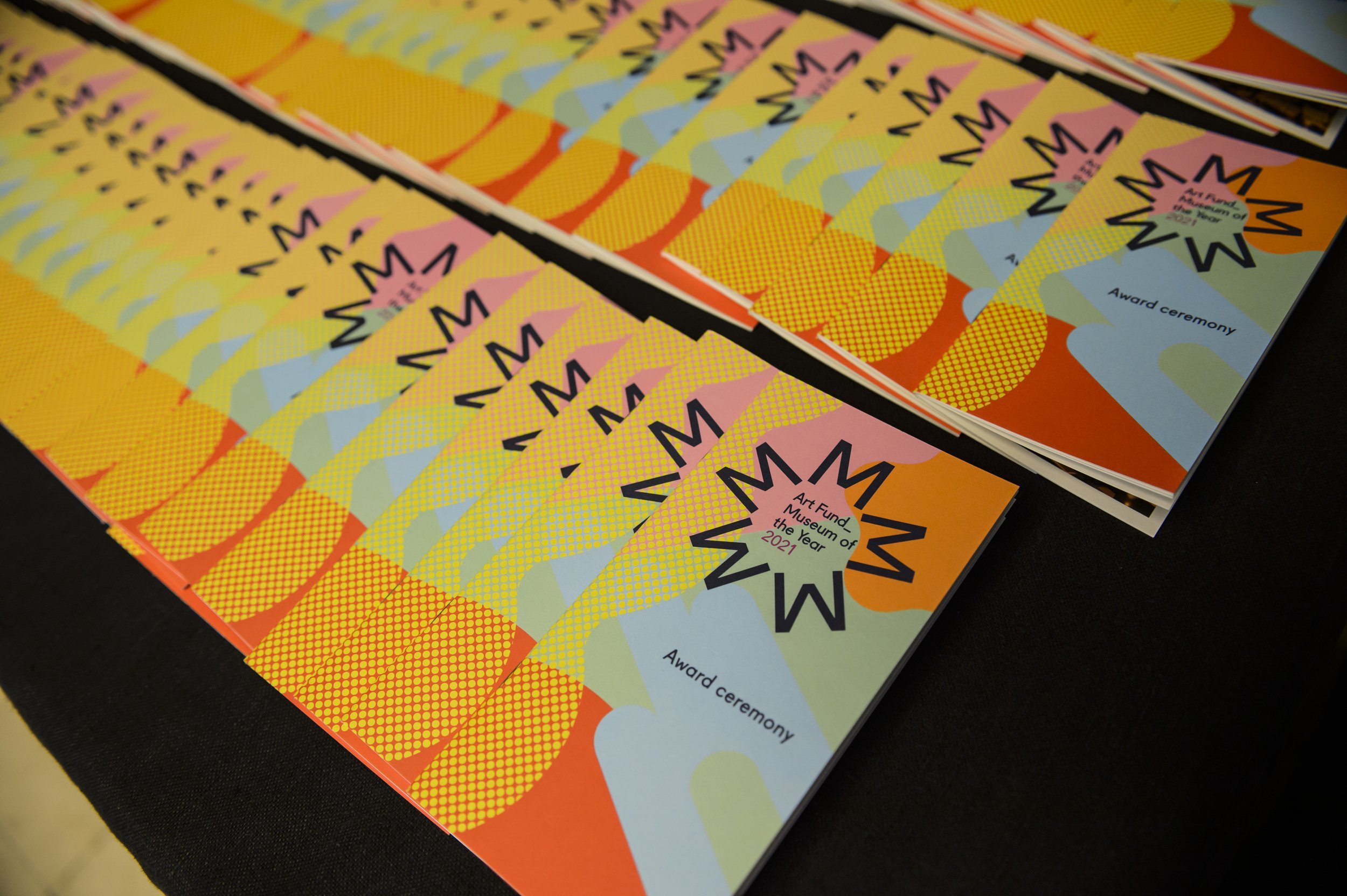 A close-up of colorful event flyers with geometric patterns and the text "Art Fund Museum of the Year 2021" and "Award ceremony".