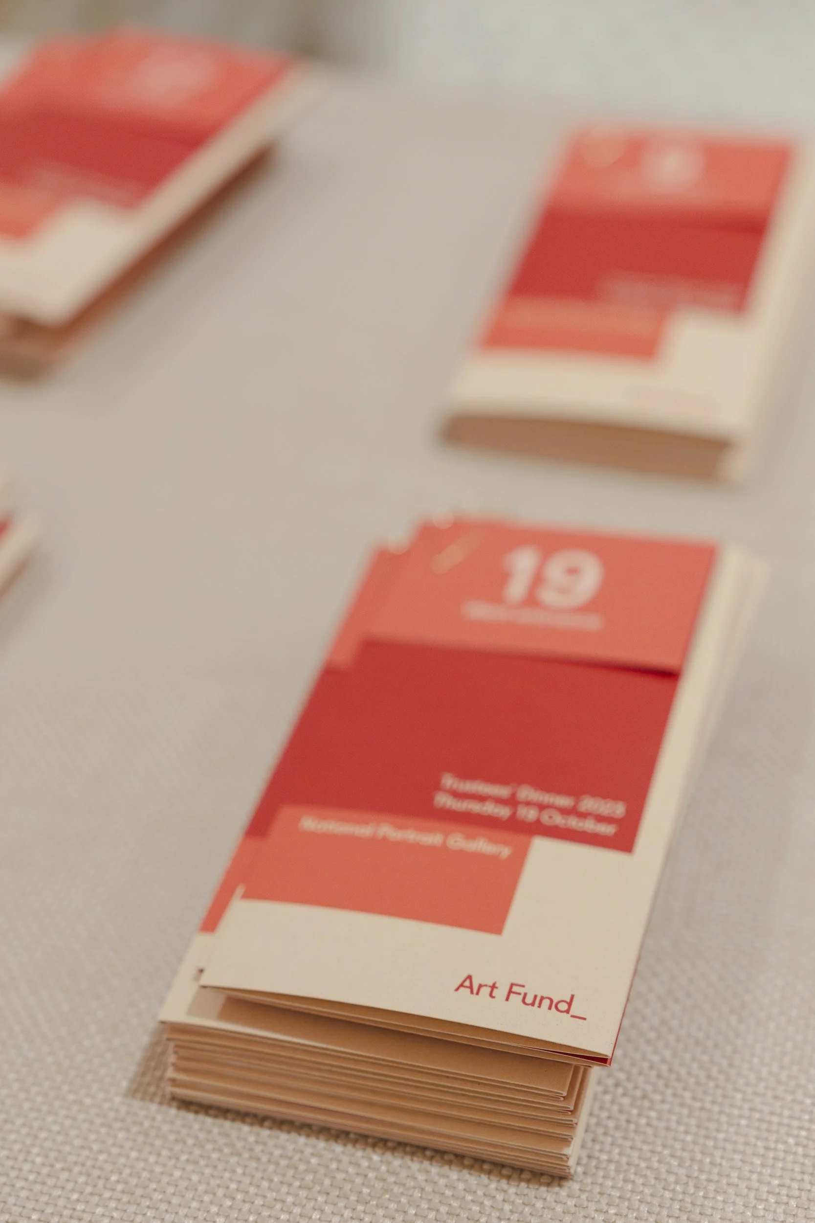 Stack of small brochures or cards with red and white designs, titled "Art Fund" on a light-colored surface.