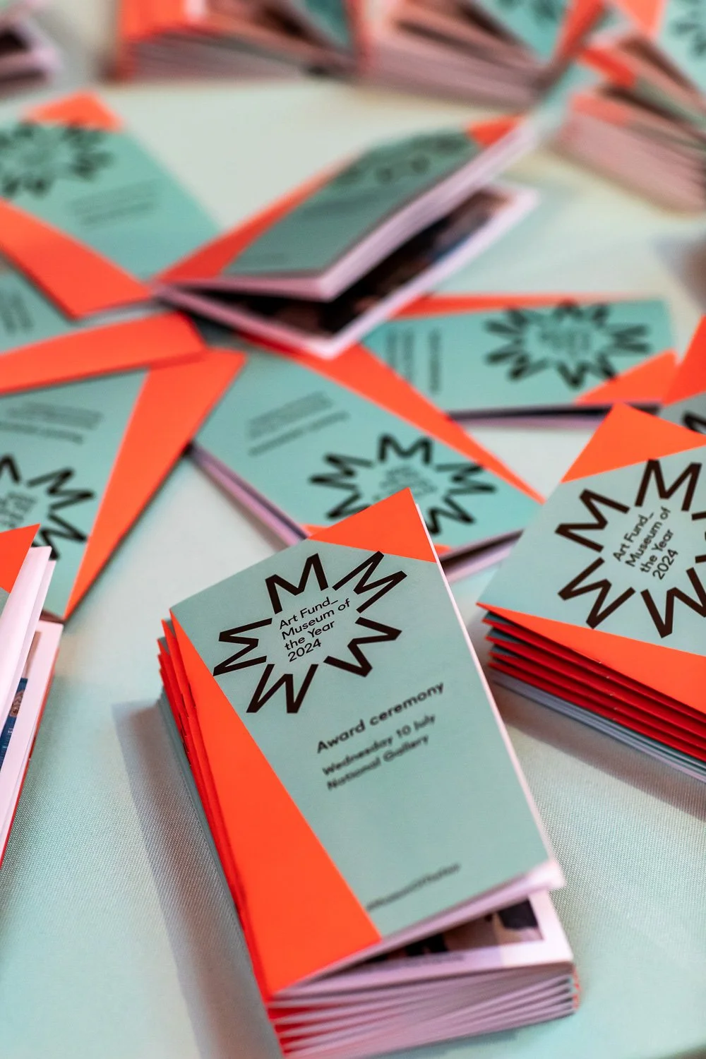 Stacks of programs for the Art Fund Museum of the Year 2024 award ceremony at the Natural History Gallery.