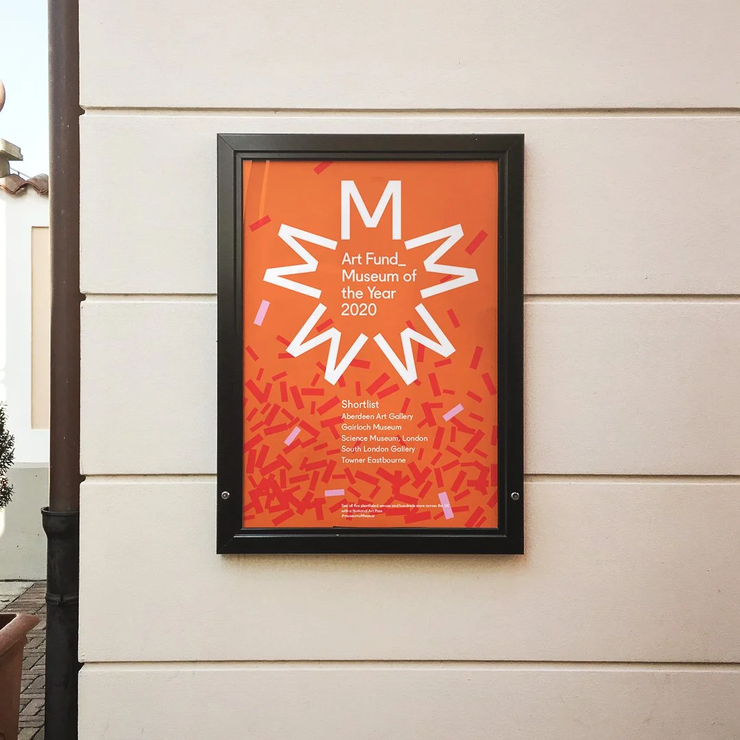 Poster on a beige wall displaying the Art Fund Museum of the Year 2020 shortlists and winners, with a large star graphic, orange background, and text listing the museums.