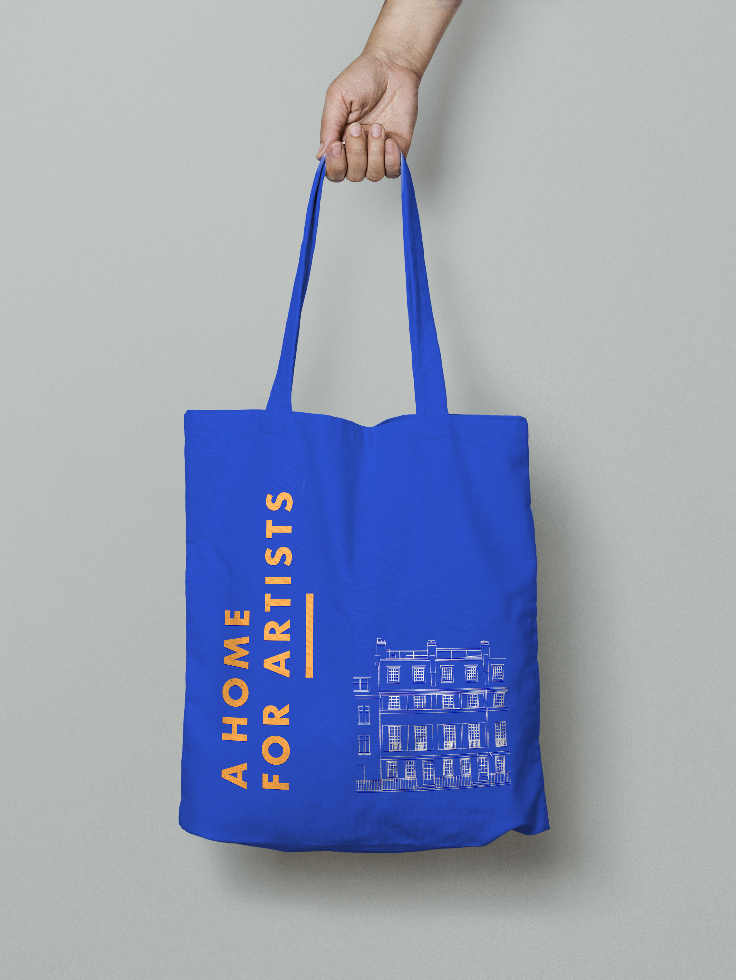 A person holding a blue tote bag with orange and white printed text and a line drawing of a building.