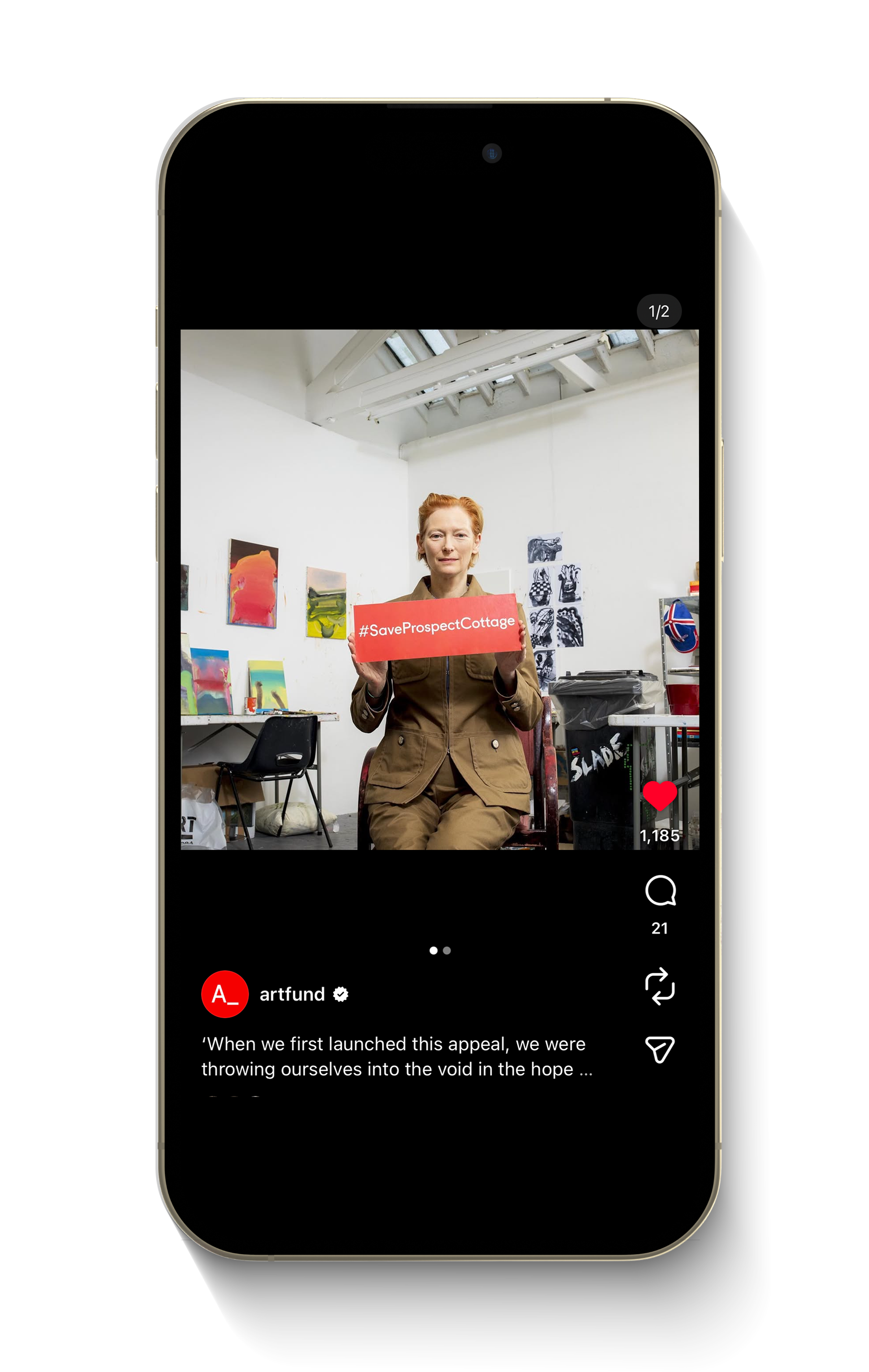 A woman with short red hair sitting in an art studio or gallery space, holding a red sign that reads '#SaveProspectCottage'. The studio has white walls with colorful abstract paintings, and there are art supplies and a UK flag on a shelf in the backg
