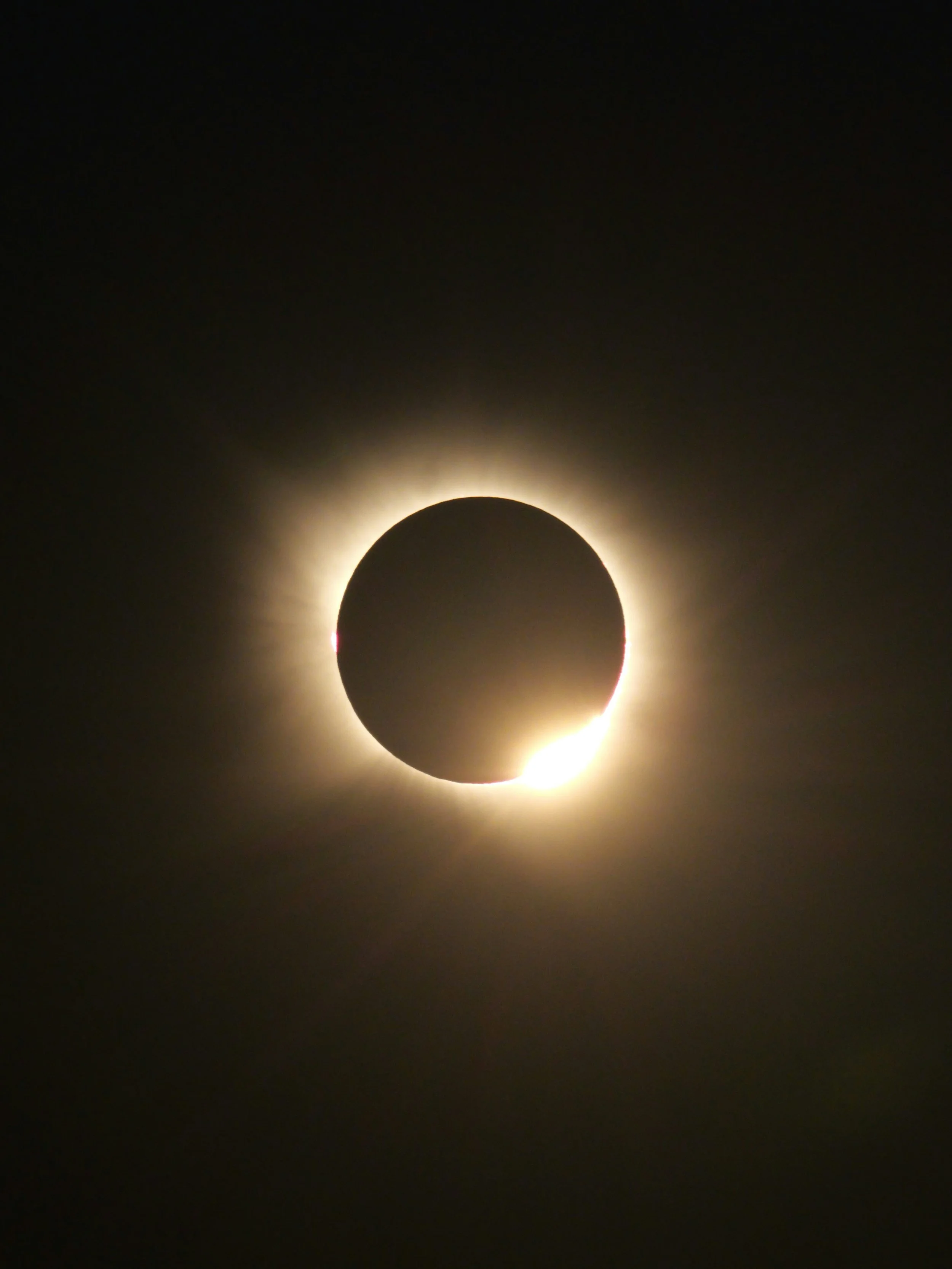 Total solar eclipse with the moon blocking the sun, creating a dark silhouette with a bright corona surrounding the moon.