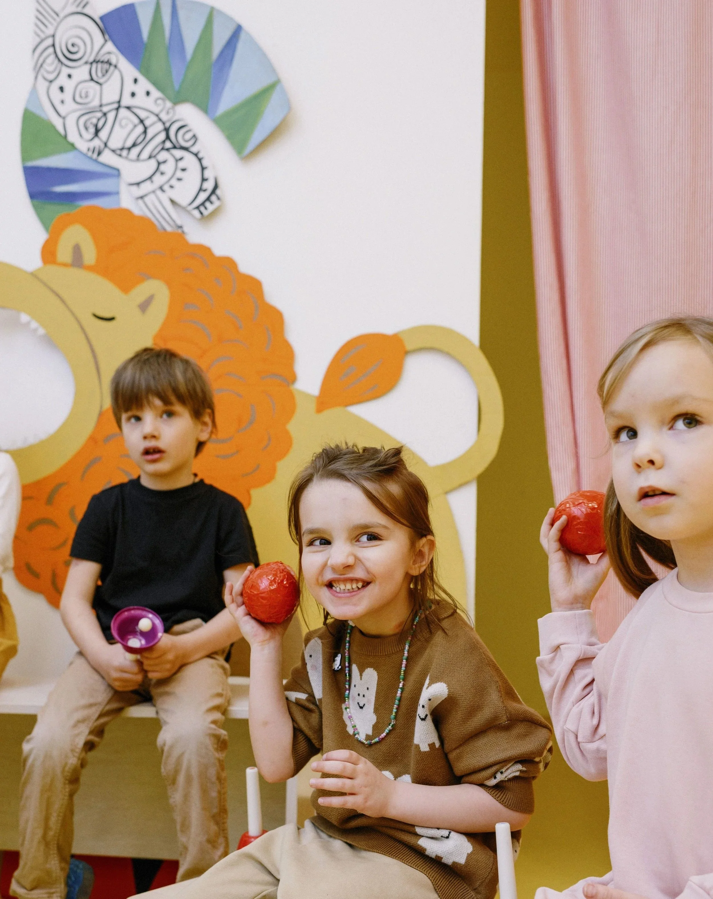Young children participating in a fun, play-based English language learning session with colorful educational props.