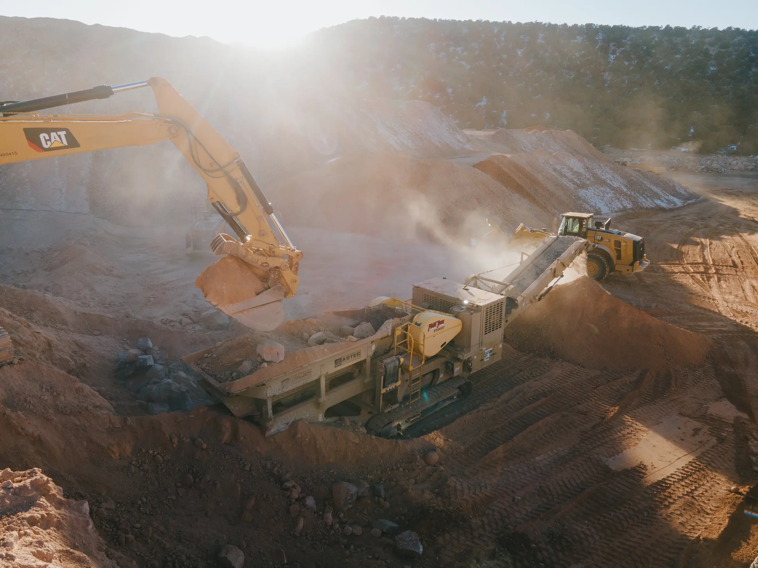 Southern Utah Construction site with large excavator moving dirt in a mountainous area during daytime with sunlight.