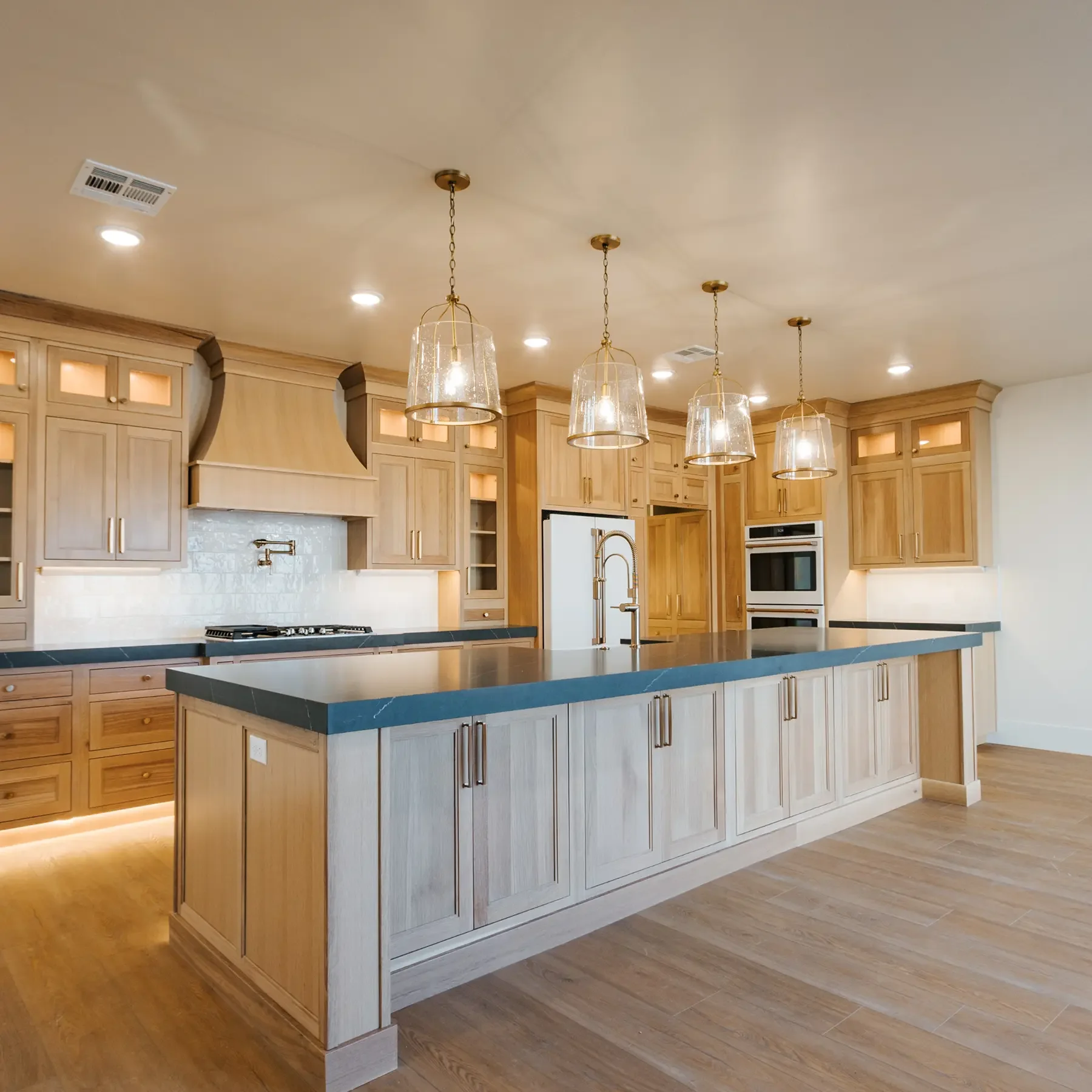 Modern, luxury kitchen. Beautiful light brown wooden cabinets, with tile backsplash and toe-kick lighting