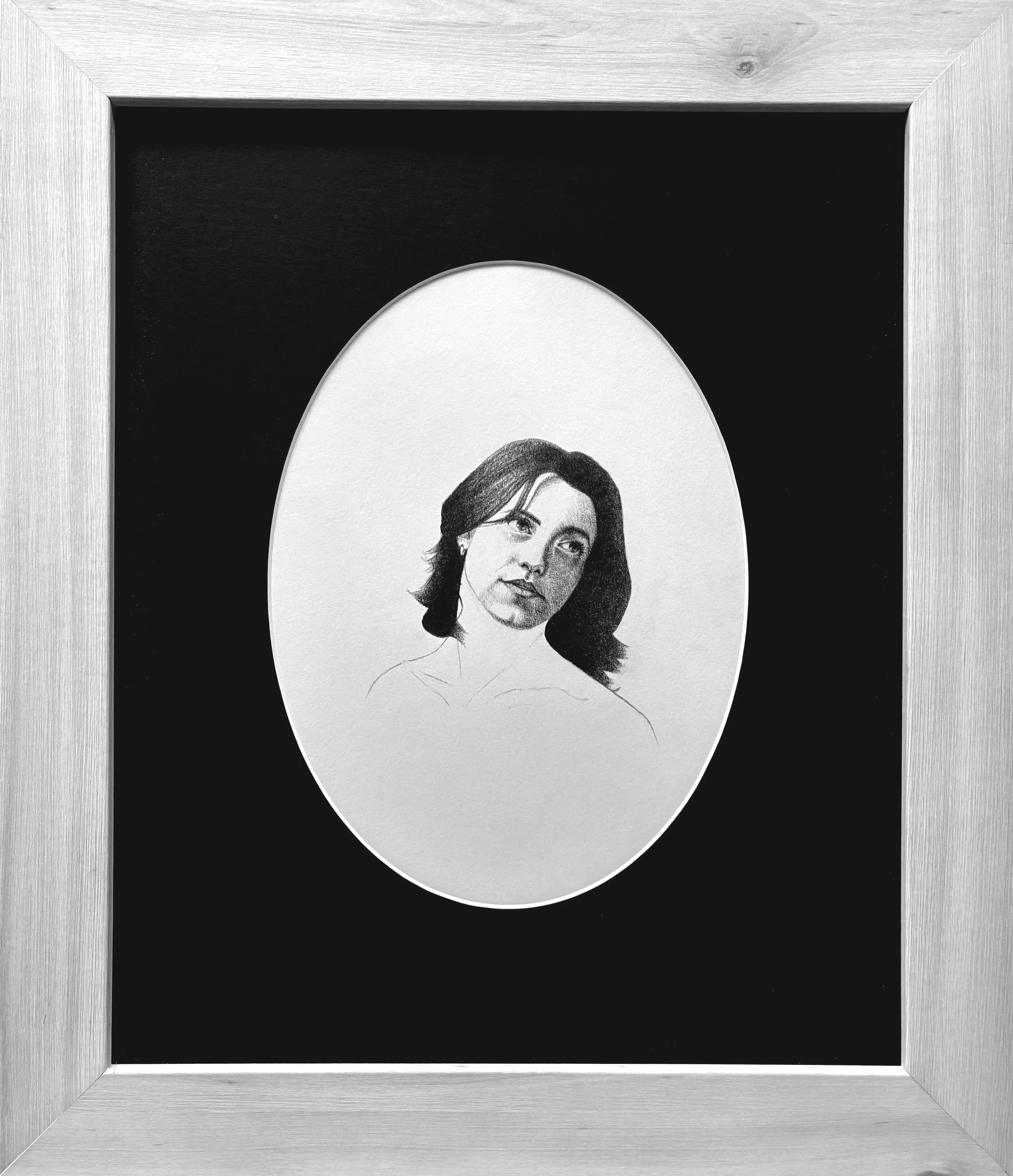 Framed black-and-white portrait of a woman with shoulder-length hair, set against a dark background.