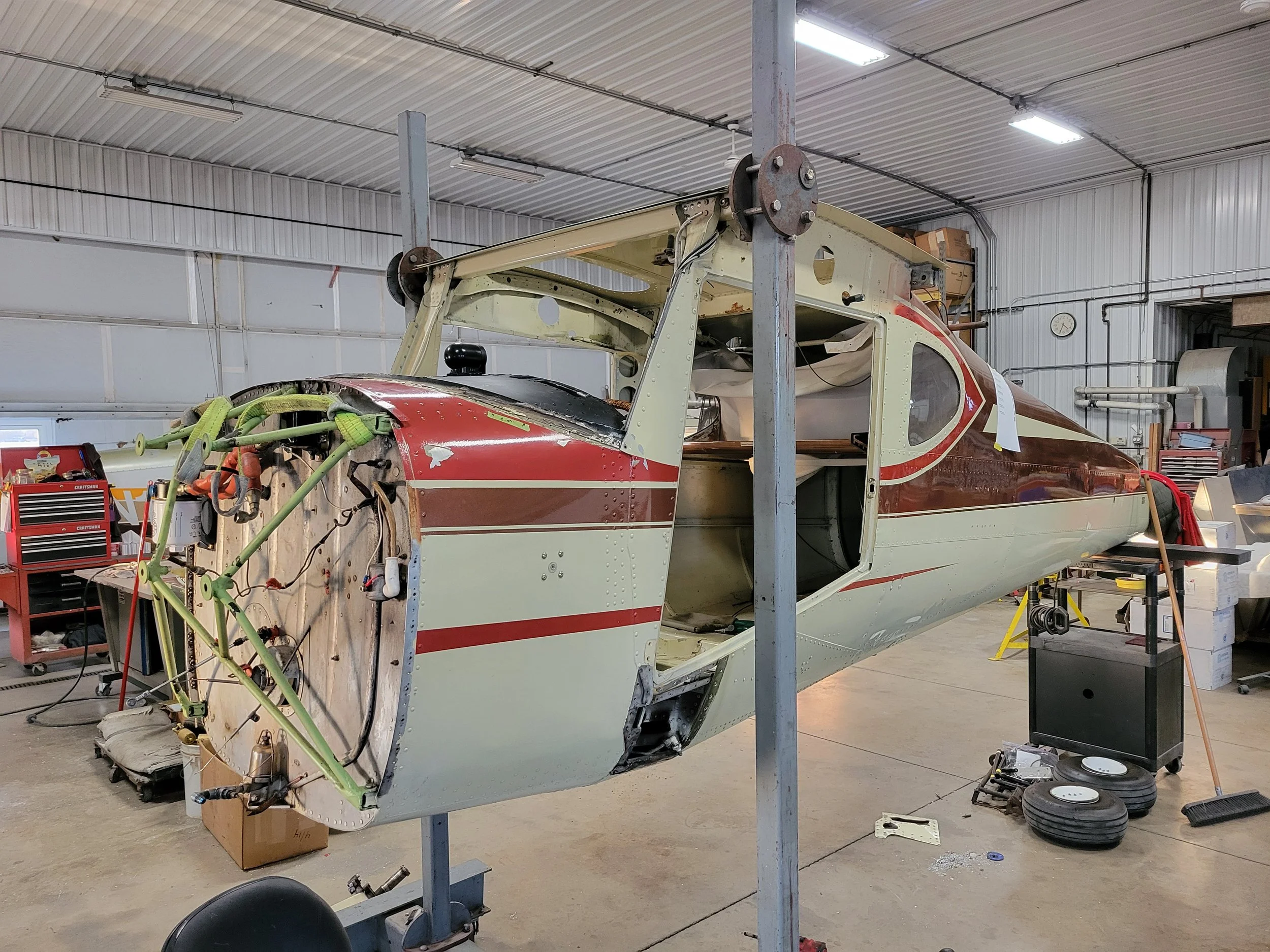 A partially assembled aircraft fuselage inside a hangar, surrounded by tools and equipment.