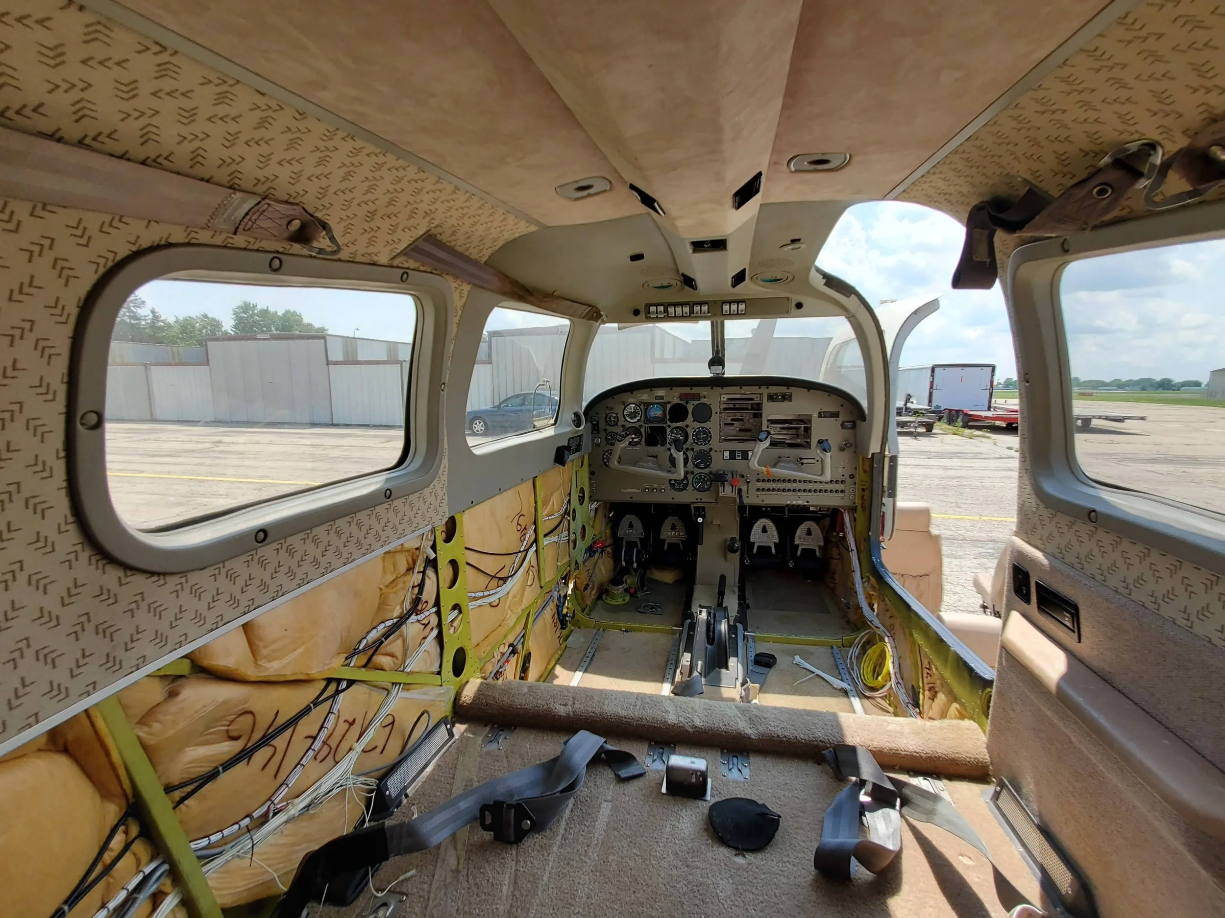 Interior view of an airplane cockpit during repair or construction, with exposed wiring and insulation, and unfinished surfaces.
