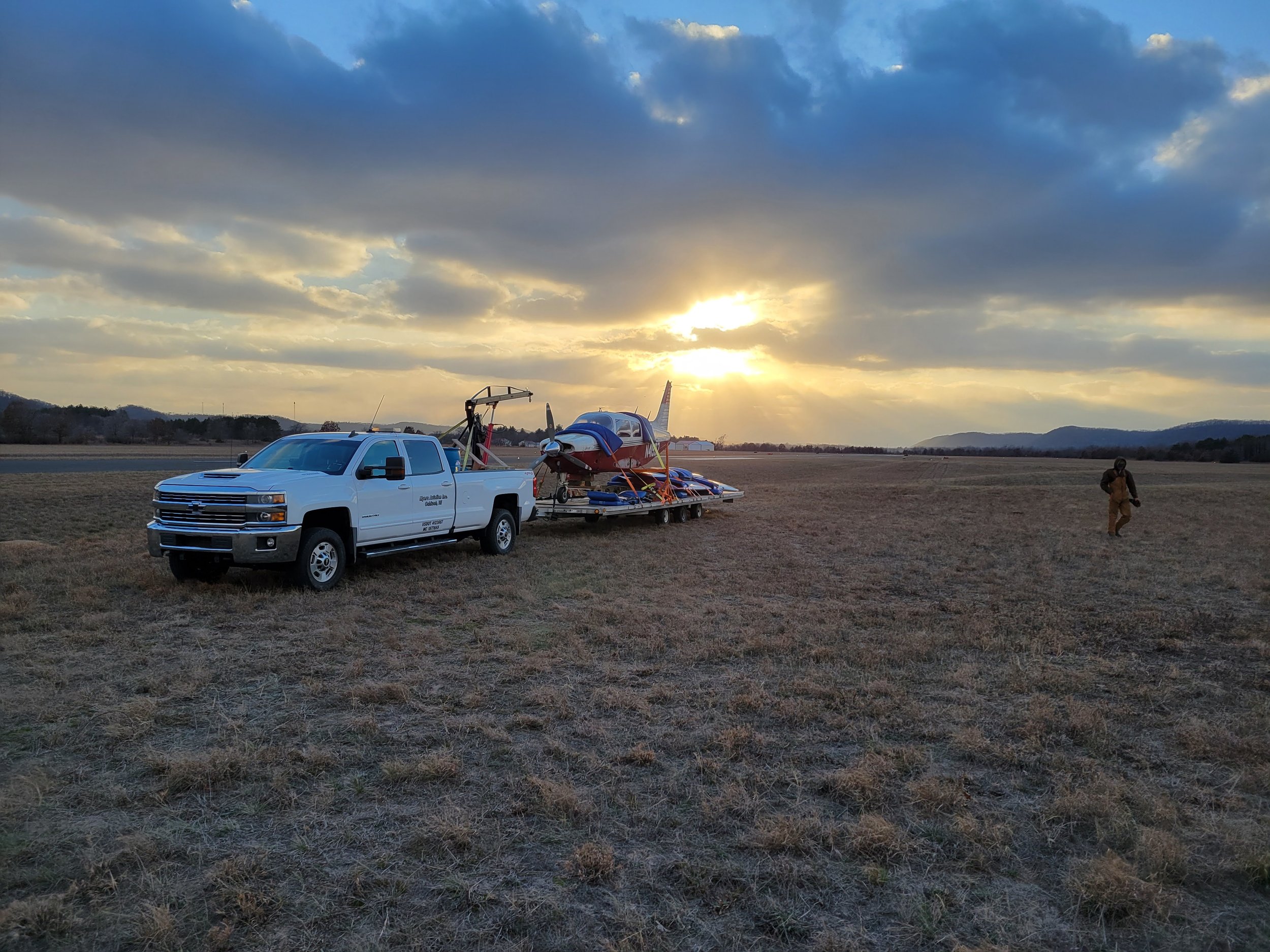 A white pickup truck with black side mirrors is parked on a grassy field.