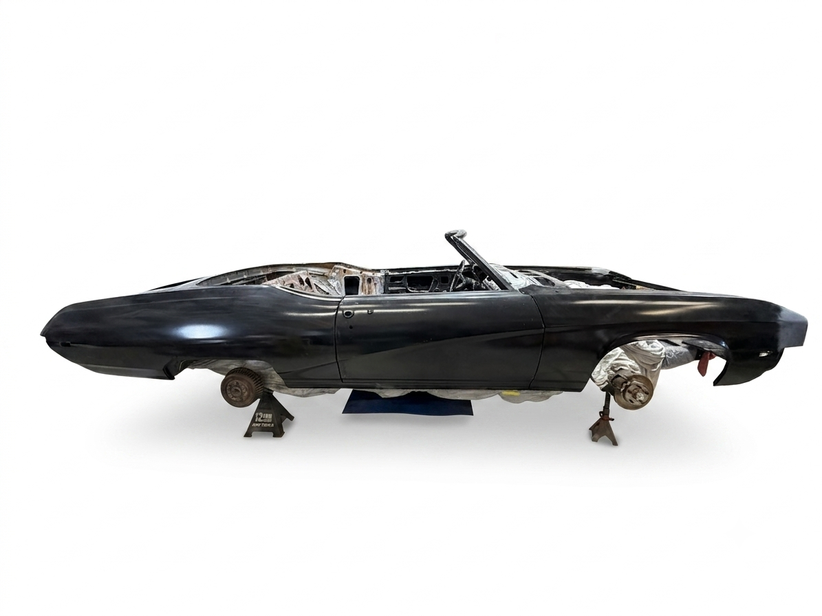 Disassembled black vintage car chassis without wheels, placed on jack stands, on a plain white background.