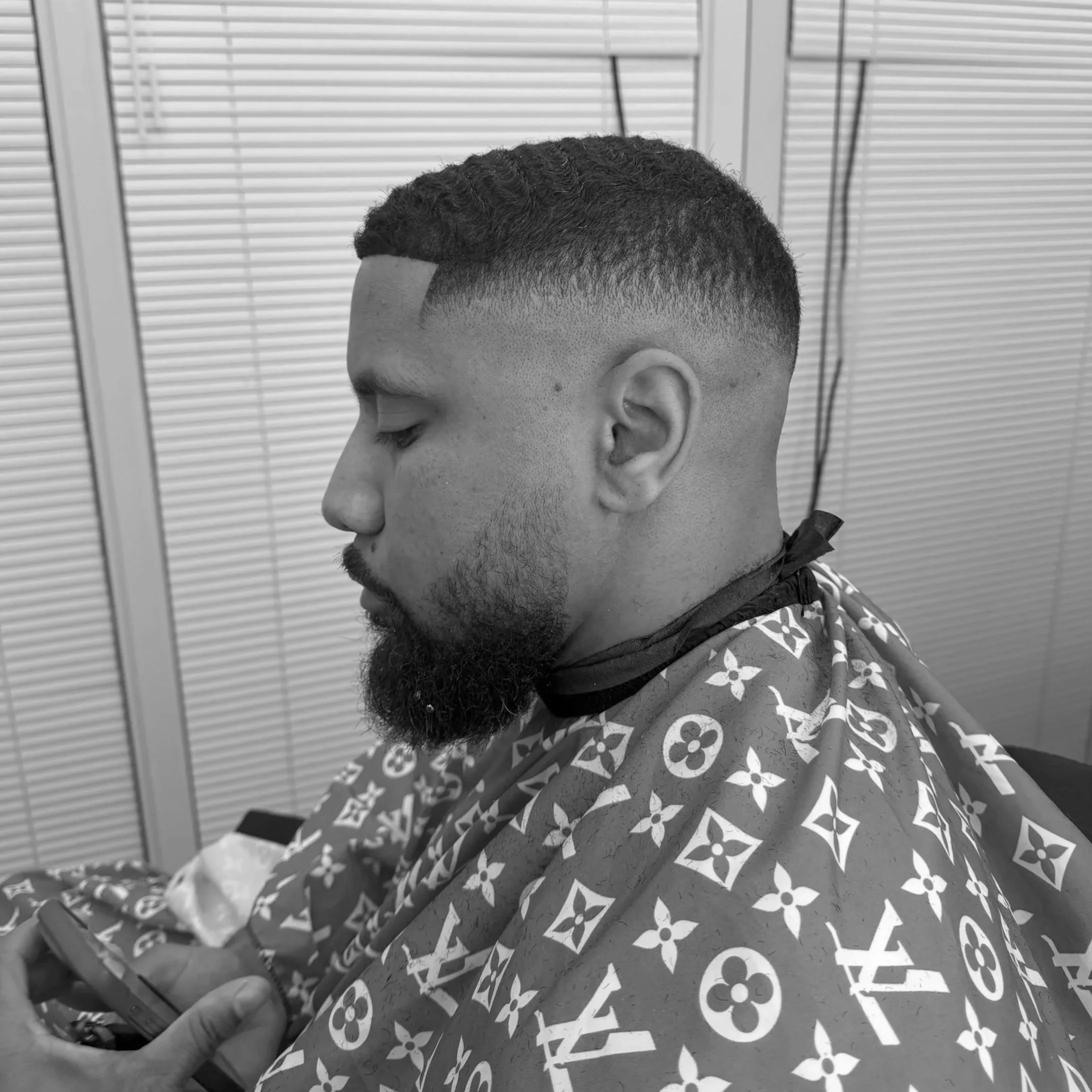 Man met krullend haar en baard tijdens een professionele haircut bij BL The Barber in Rotterdam