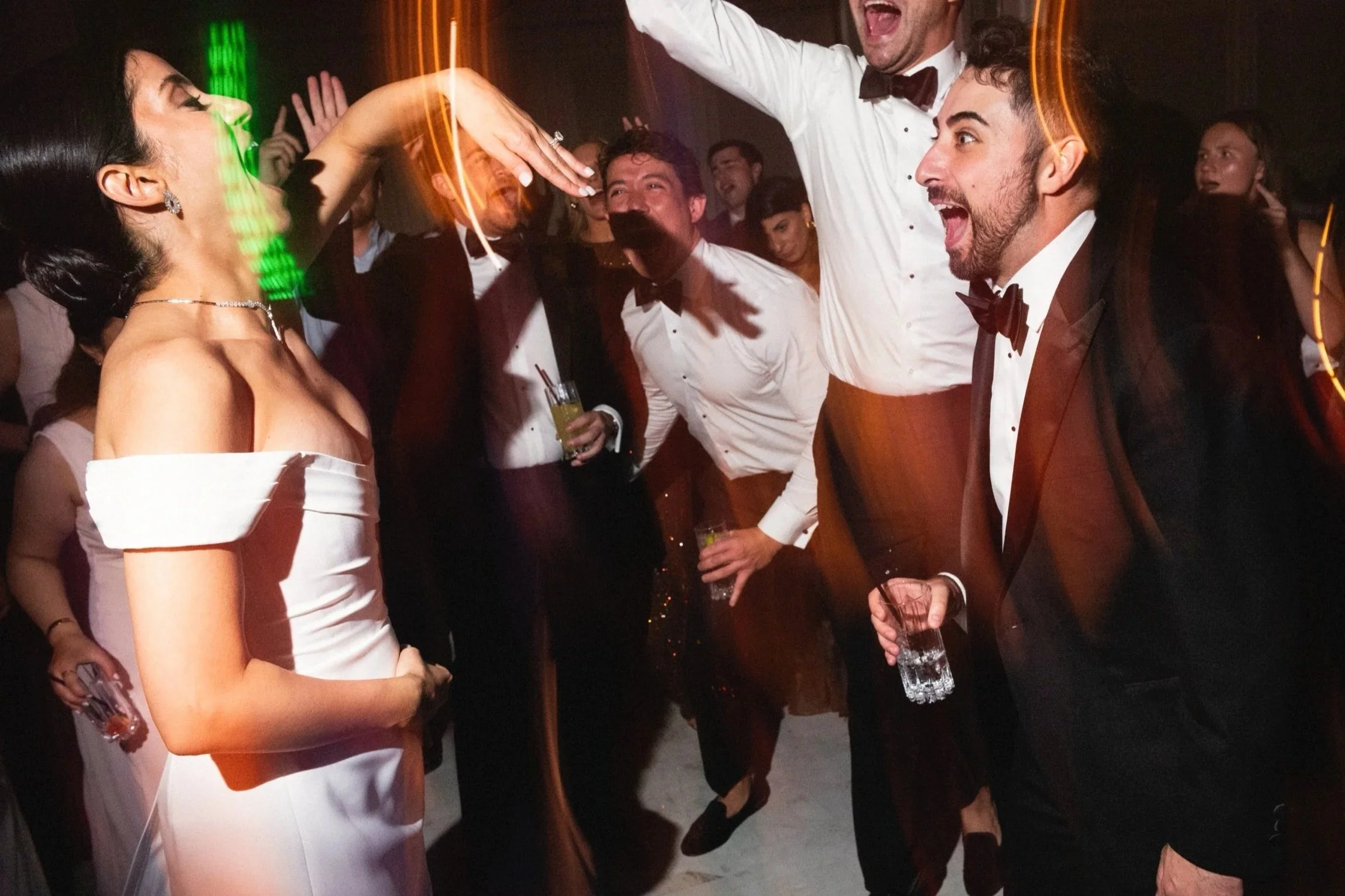 People dressed in formal attire dancing and celebrating at a party or wedding reception.
