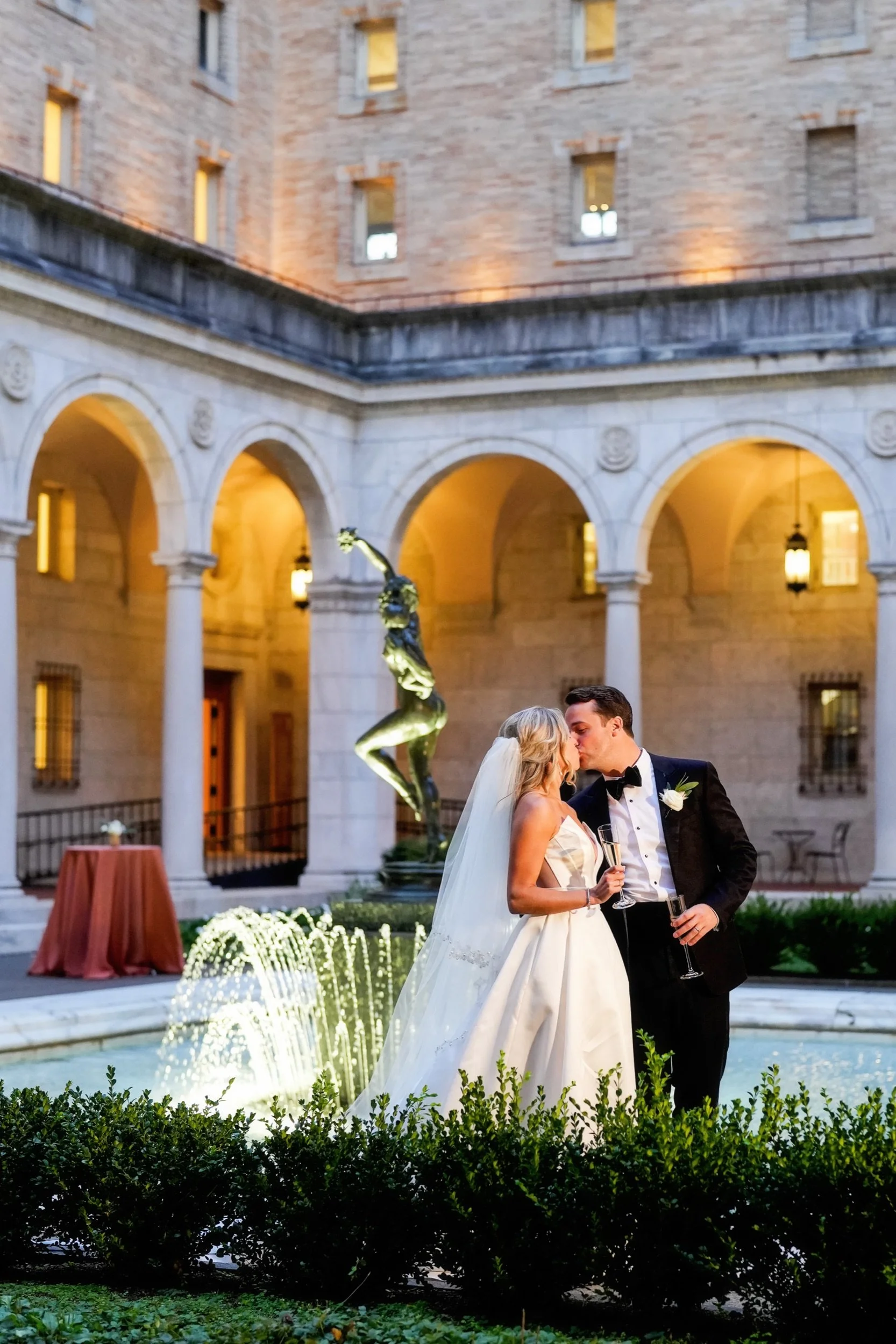 Couple sharing a kiss in front of a stautue in the Boston Public Library courtyard