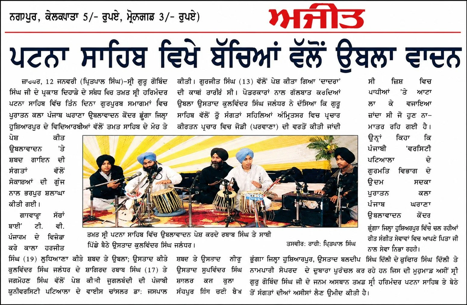 Photograph of a musical performance with five men in traditional Sikh attire, playing classical instruments on stage with a decorative yellow background and potted plant.