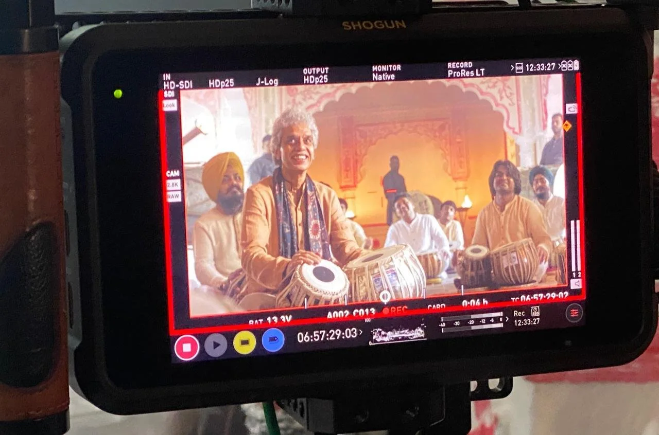 Filming a group of musicians performing traditional Indian drums in a decorated temple setting.