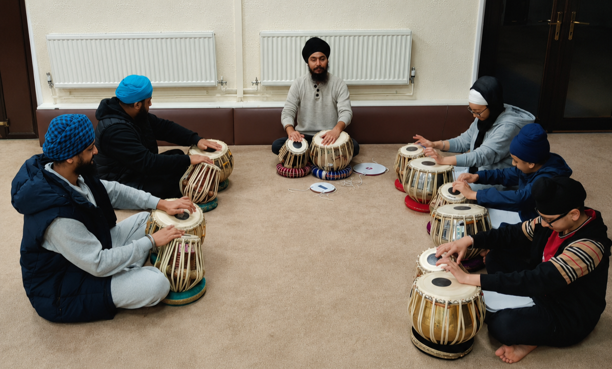 Group of people sitting on the floor and playing traditional drums in a circle.
