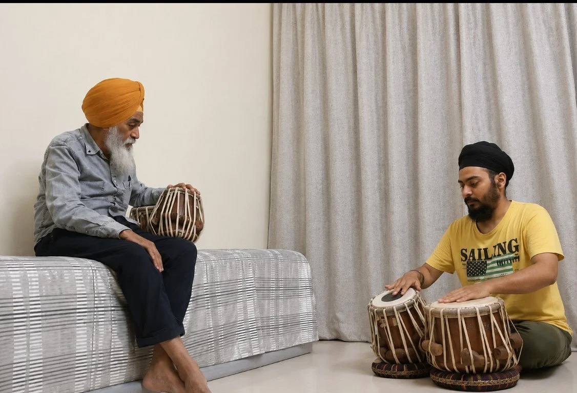 Two men sitting on the floor and on a bed, playing traditional Indian drums.