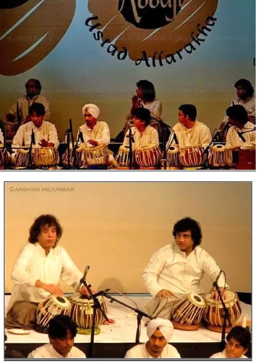Group of performers playing traditional Indian drums called tablas, sitting on stage, with a backdrop that reads 'Gandhar MJJUMDAR' and features a large circular logo.