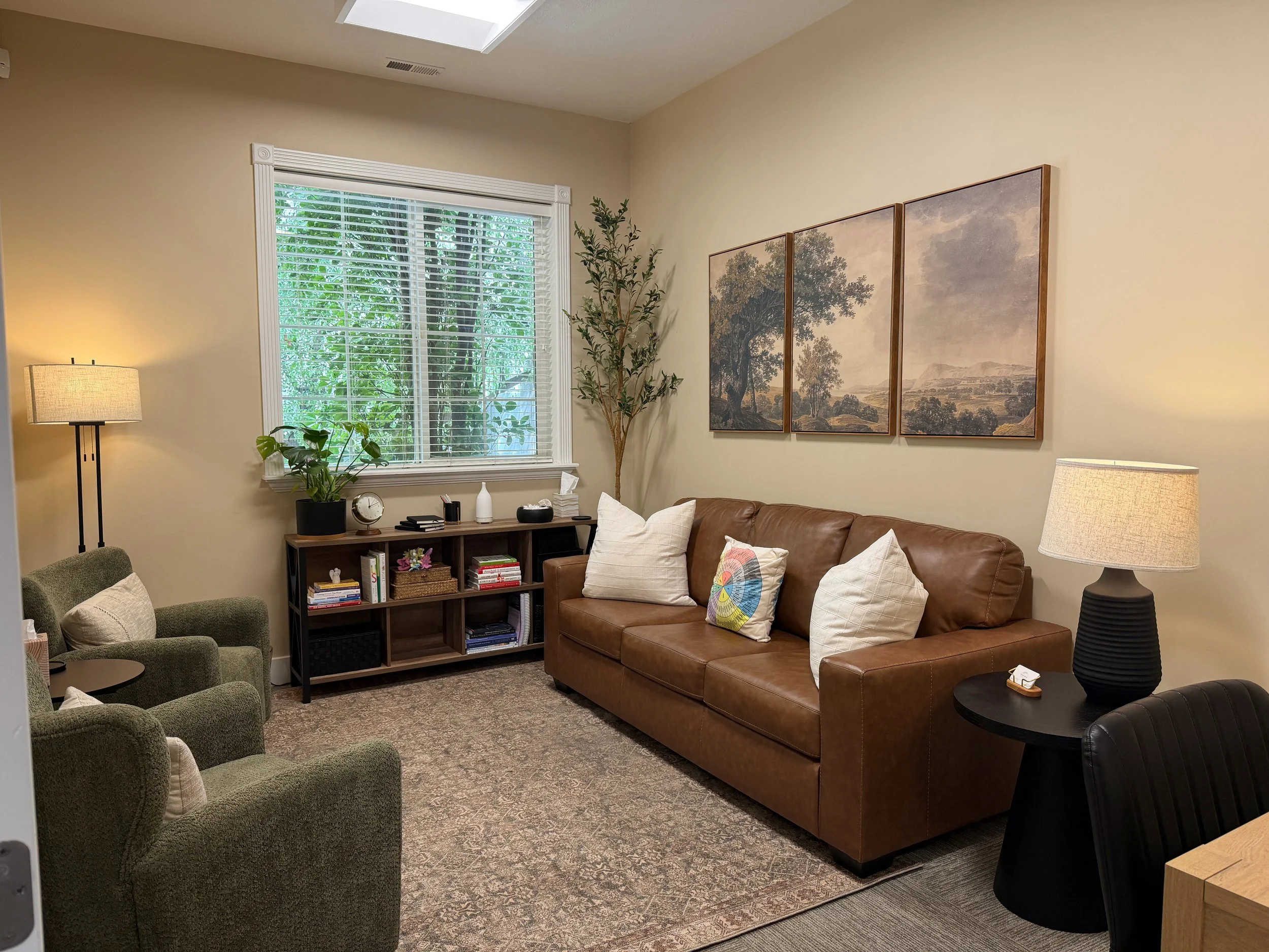 Willow Brook Counseling Center office in Sandy, Utah, with a brown leather couch, green armchairs, and a large window.