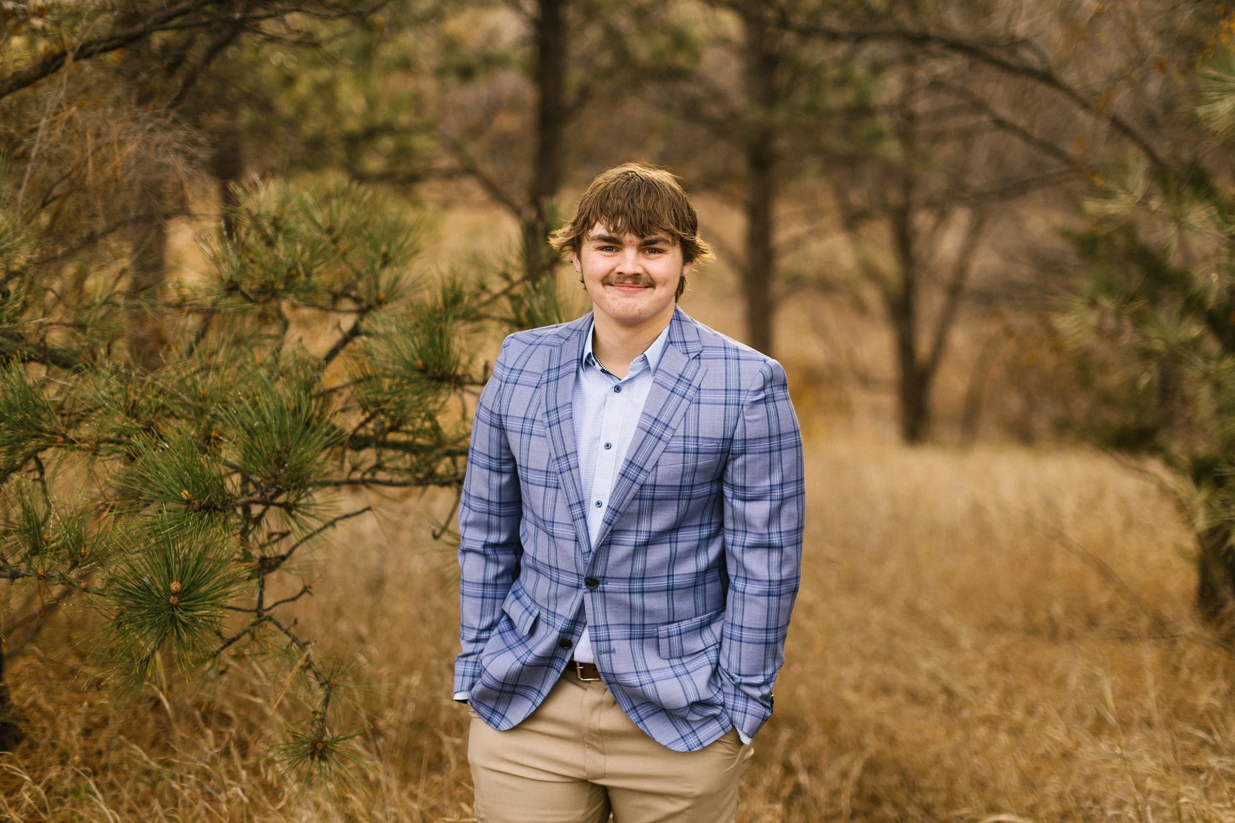 Man standing and smiling wearing a sport jacket in tall grass