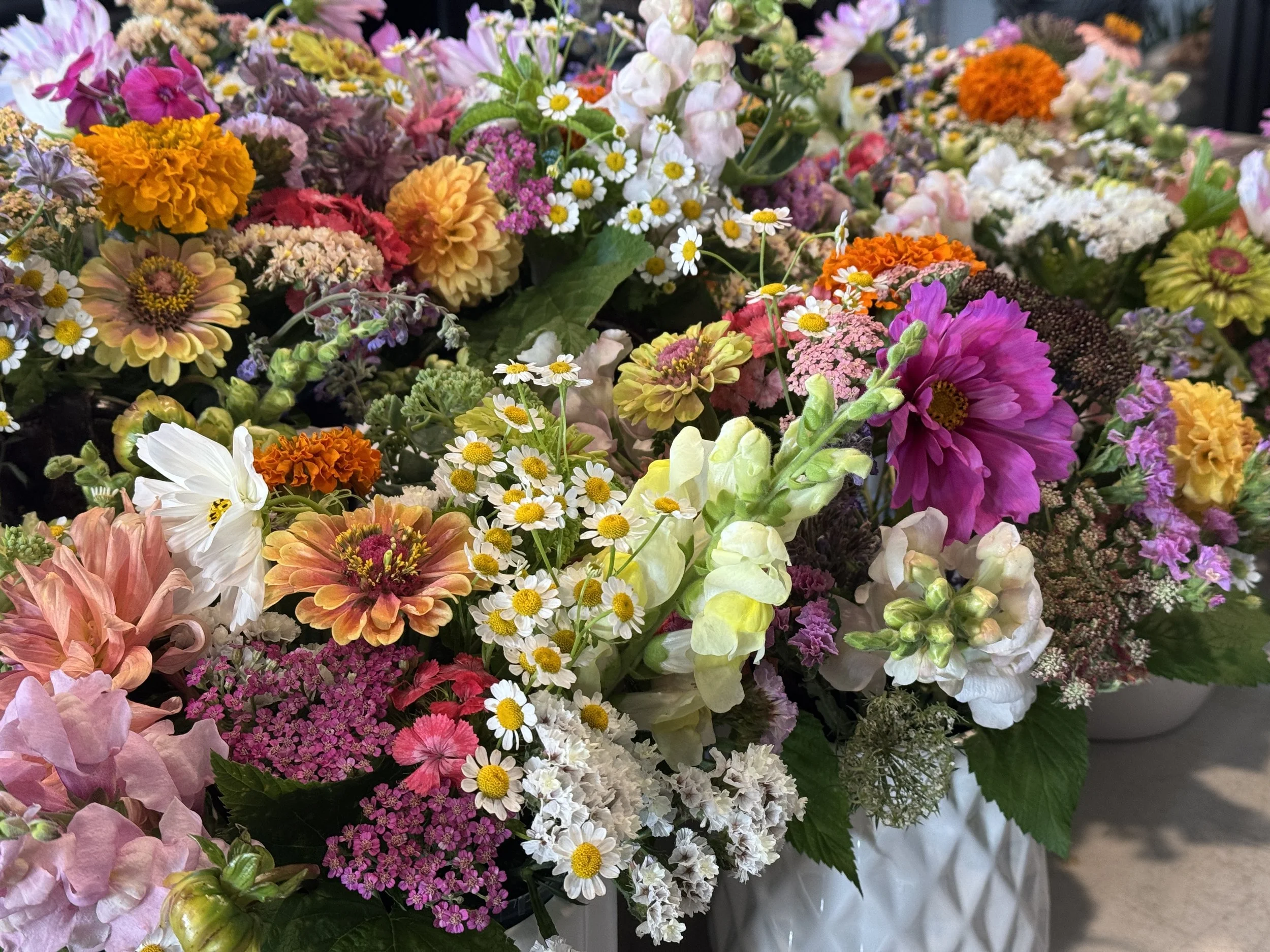 Colorful bouquet of various flowers including daisies, marigolds, zinnias, and hydrangeas.