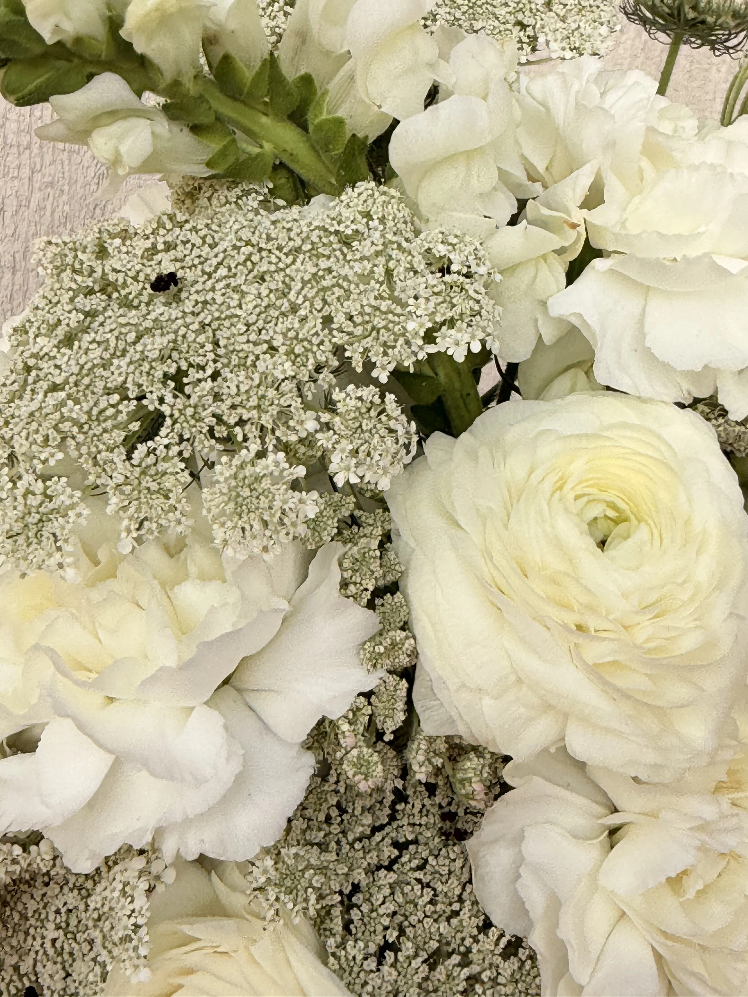 Close-up of white hydrangea, roses, and baby's breath flowers in a floral arrangement.