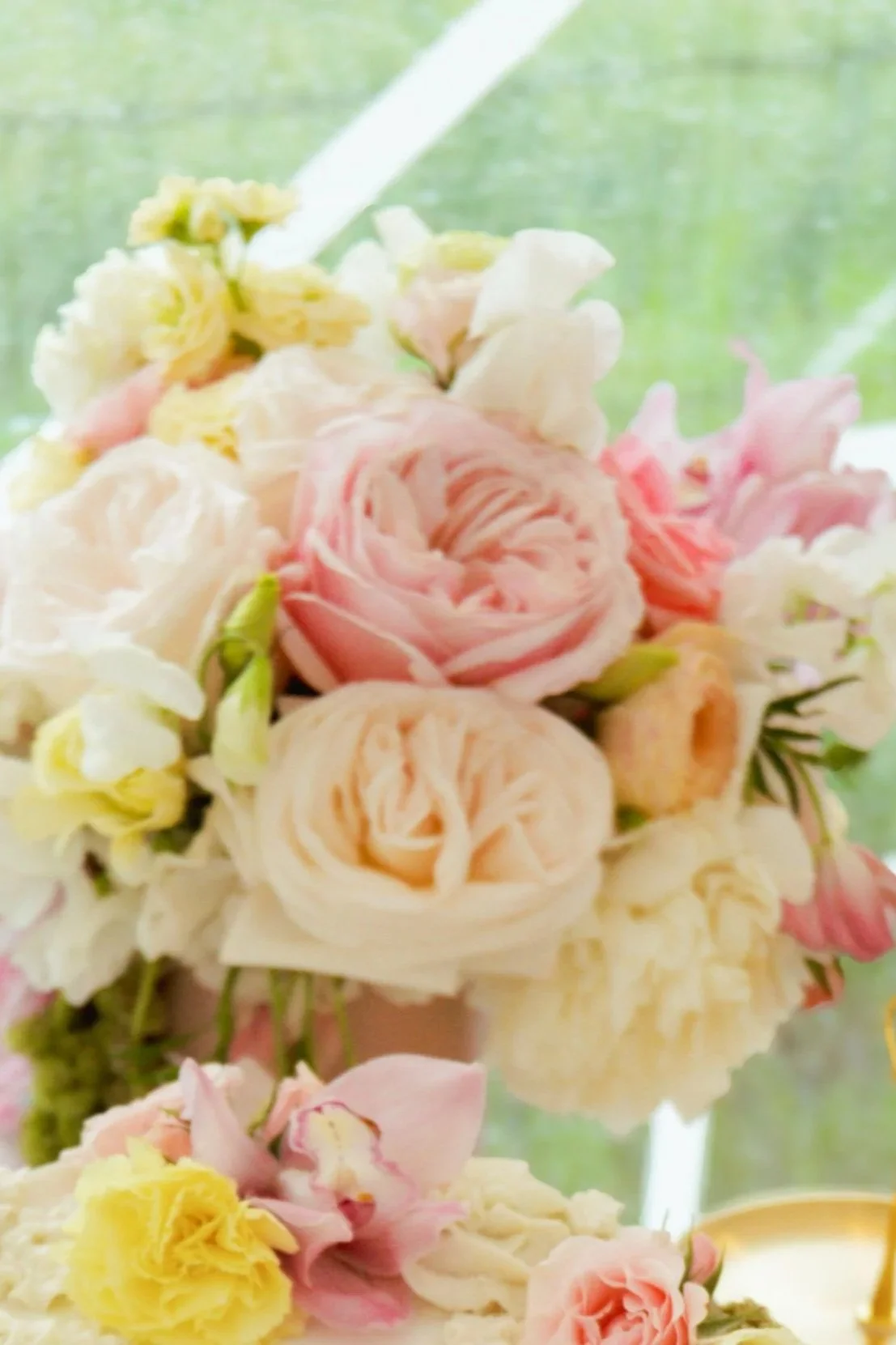 Close-up of a bouquet of pink and white roses and other flowers, with a blurred green background.