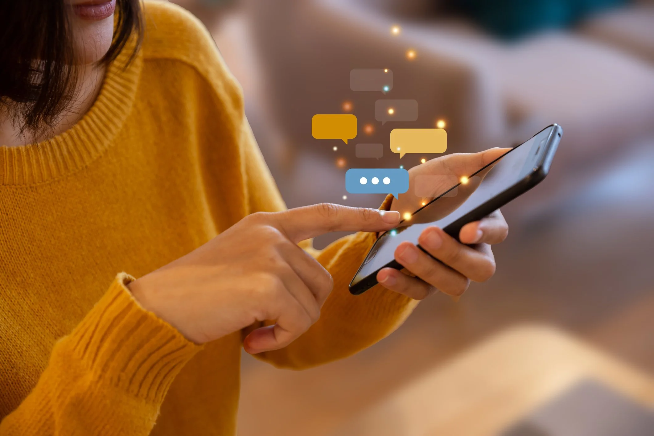 Close-up of a person in a mustard yellow sweater holding a smartphone, with colorful chat bubbles and sparkles floating around.