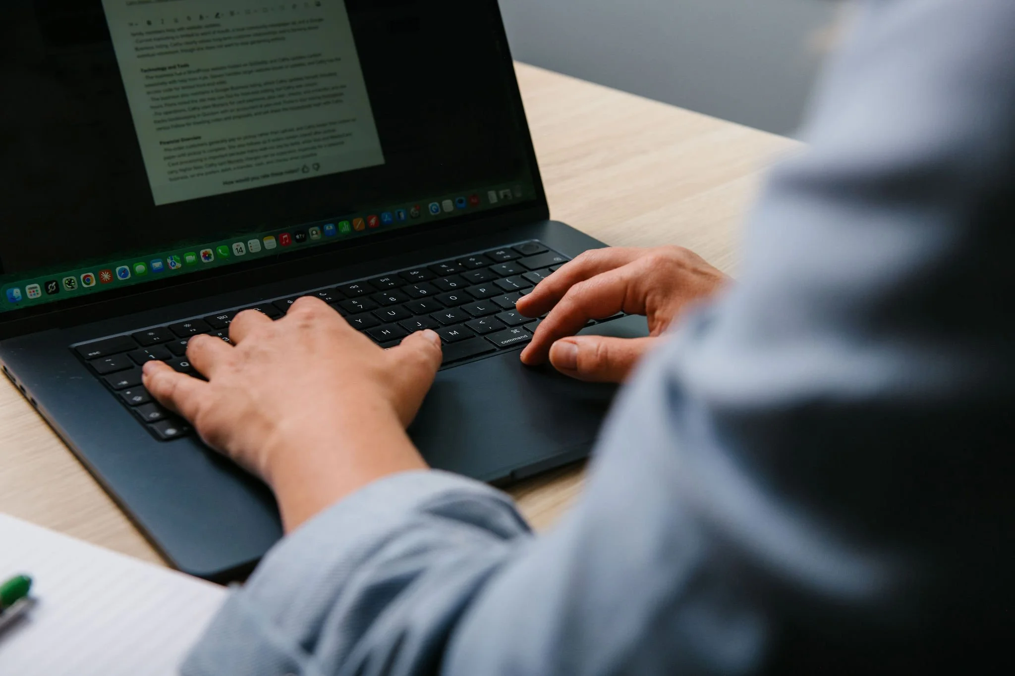 Close-up of a person typing on a laptop keyboard at a desk.