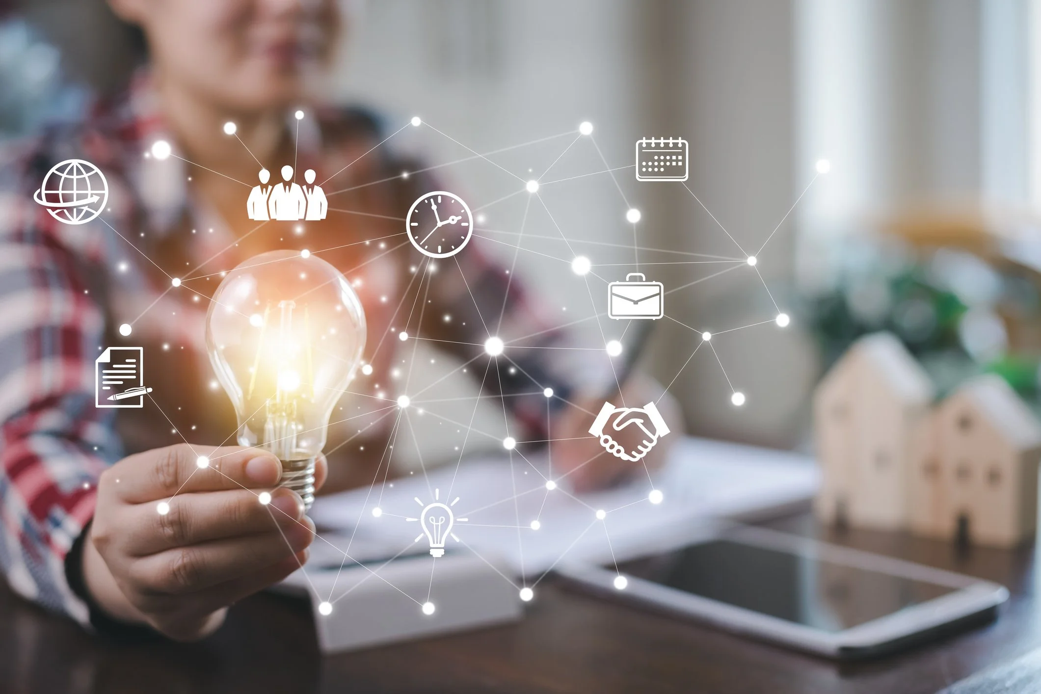 Person holding a lightbulb with digital icons representing networking, teamwork, time, calendar, business, communication, and ideas floating around.