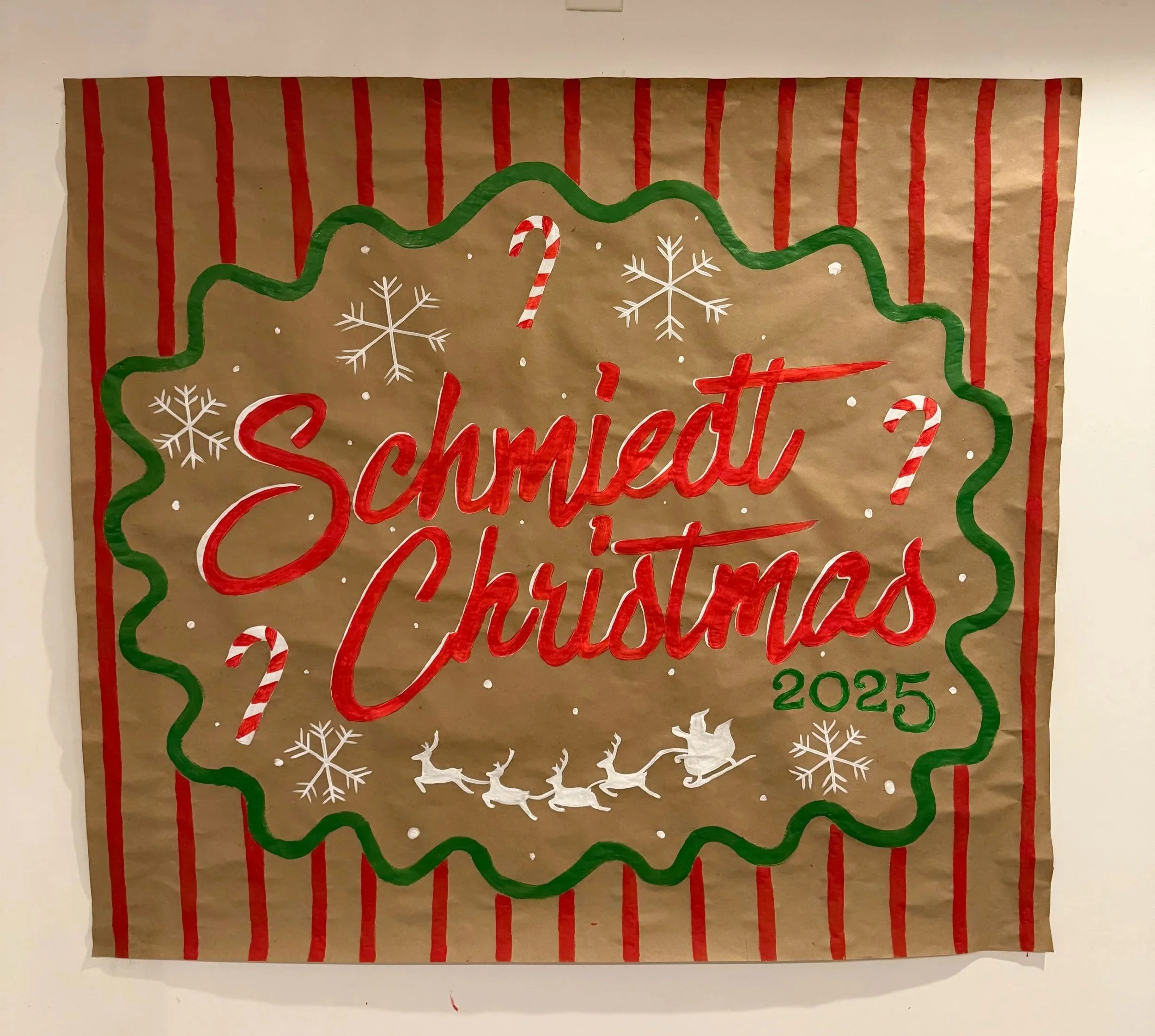 banner that says Schmiedt Christmas 2025  in a wavy green circle with red stripes behind it. with snowflakes, candy canes, and Santa's sleigh with reindeer flying at the bottom.