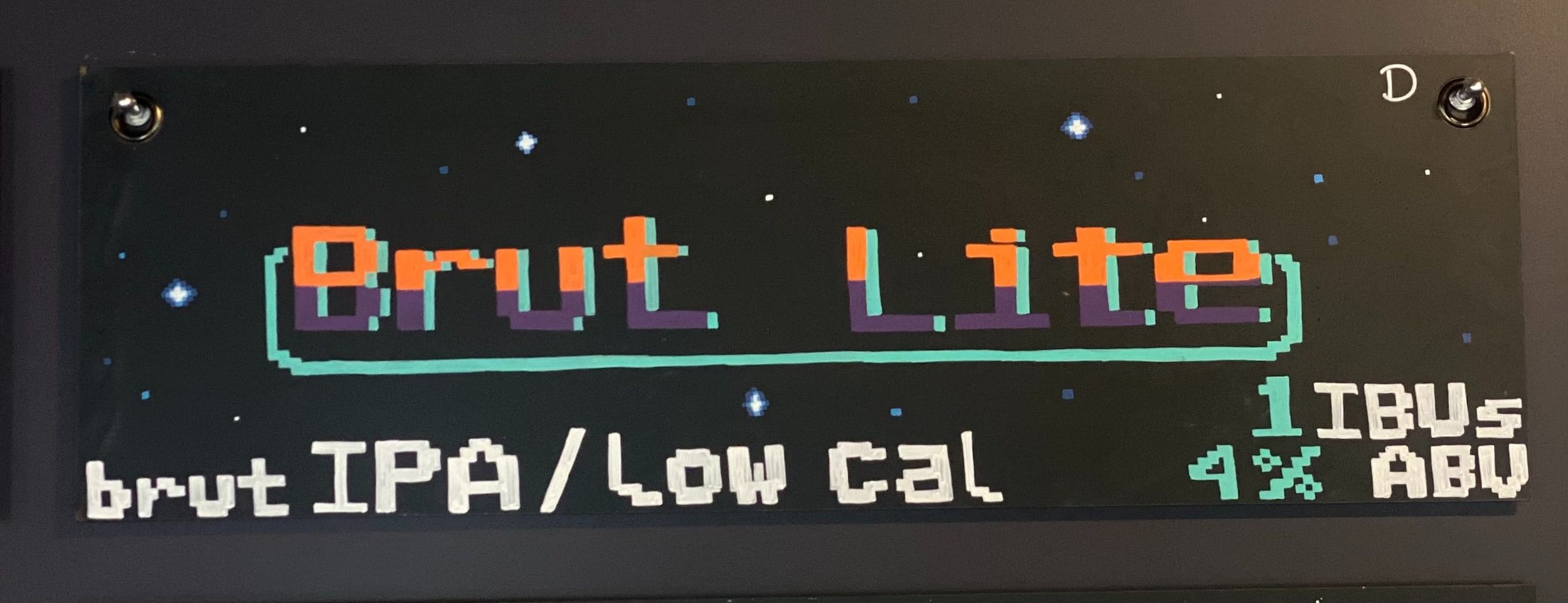 Chalk design of a vintage-inspired video game. Says Brut Lite in pixel letter font. in blue, orange, and purple. Says Brut IPA/low cal at the bottom.