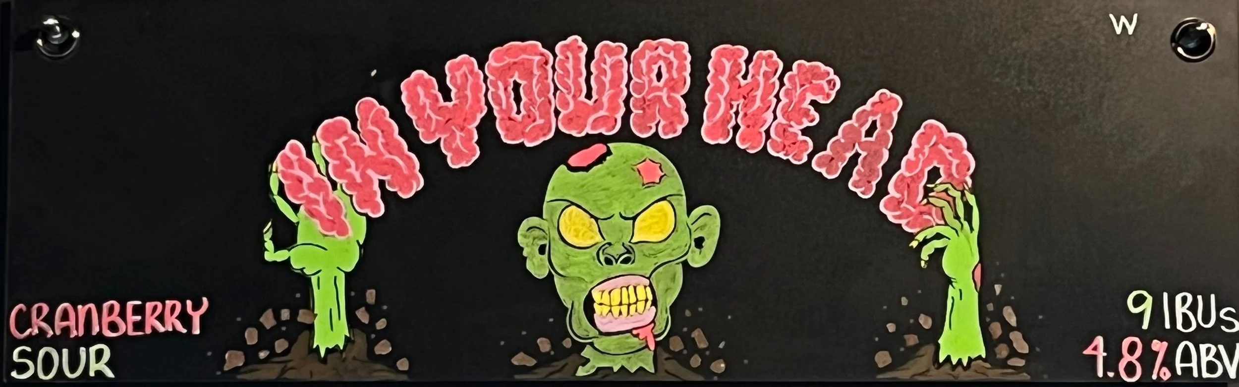 Chalk design that says in your head in brain-inspired font with a zombie character holding the words, and he's coming out of the ground. With pieces of dirt flying out of the bottom. Says cranberry sour on the left. 