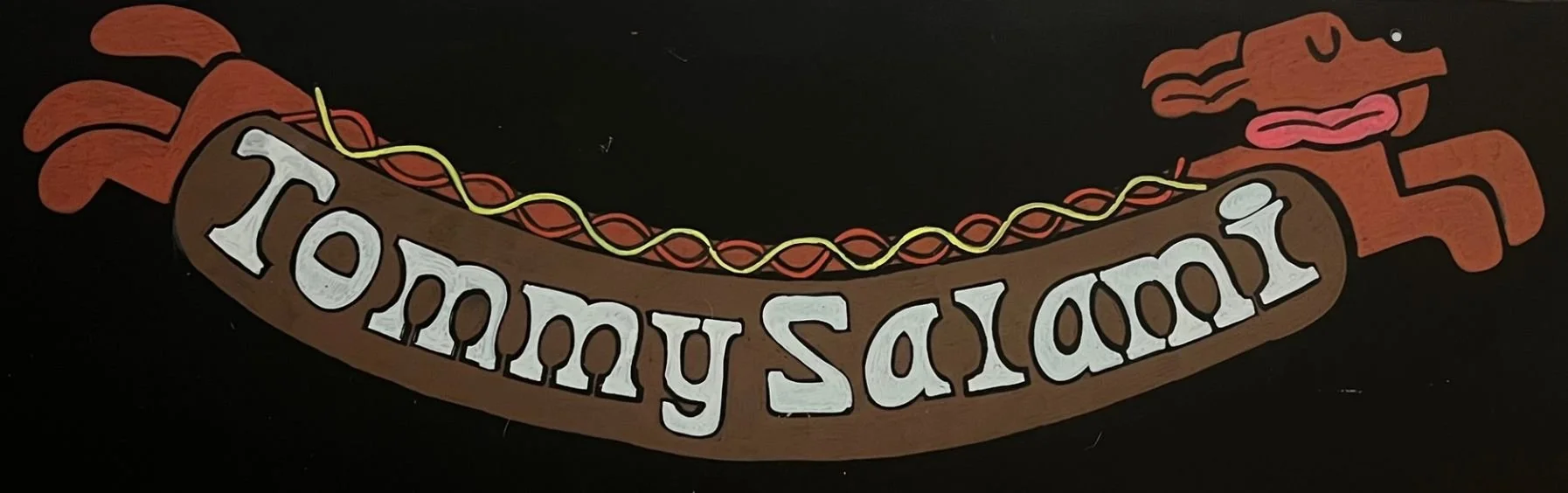 Chalk design of a wiener dog as a hot dog. On the bun says Tommy salami.