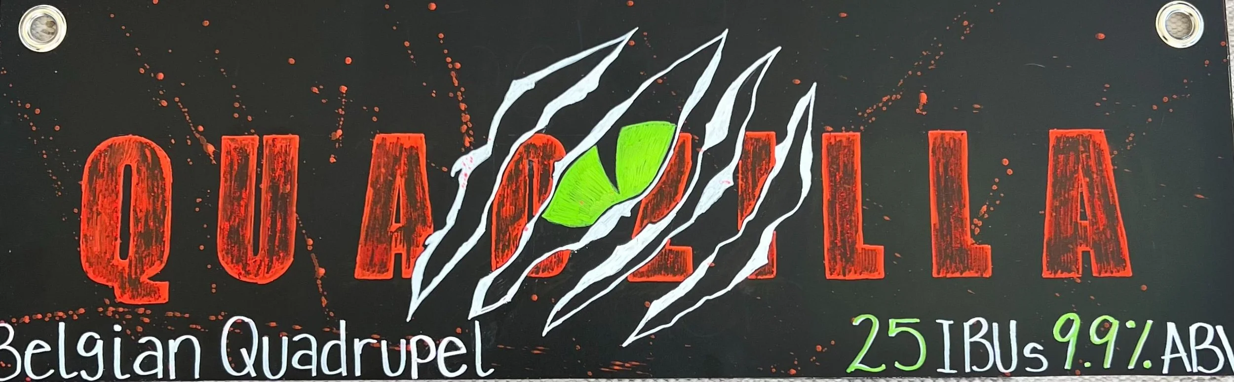 Chalk design that says quadzilla in red with a drawing of a slash in the middle like Godzilla slashed through the wall. With a green eye, you can see through it. says Belgian quadruple at the bottom