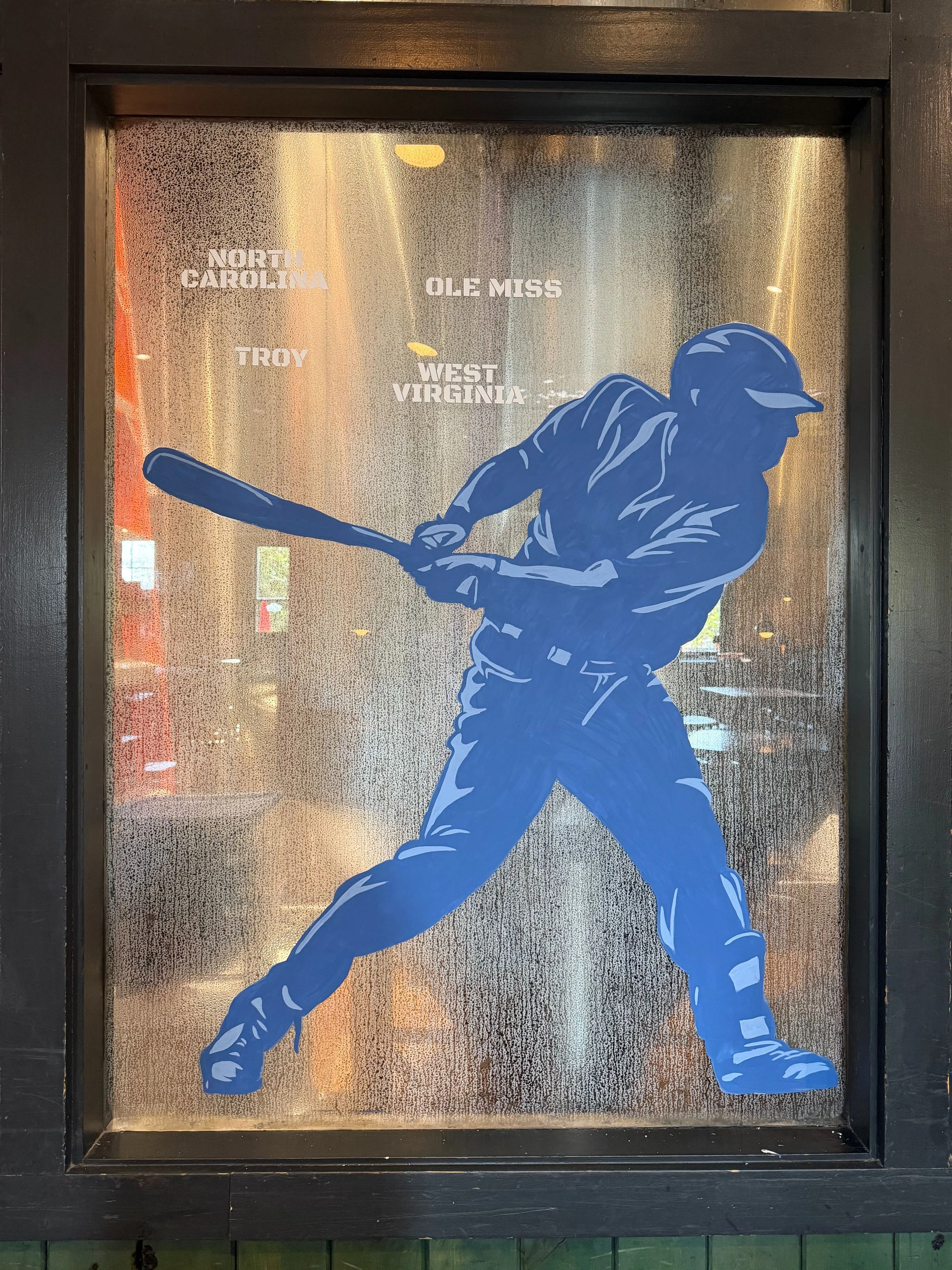 silhouette of a baseball player painted in blue hitting a baseball painted on a window